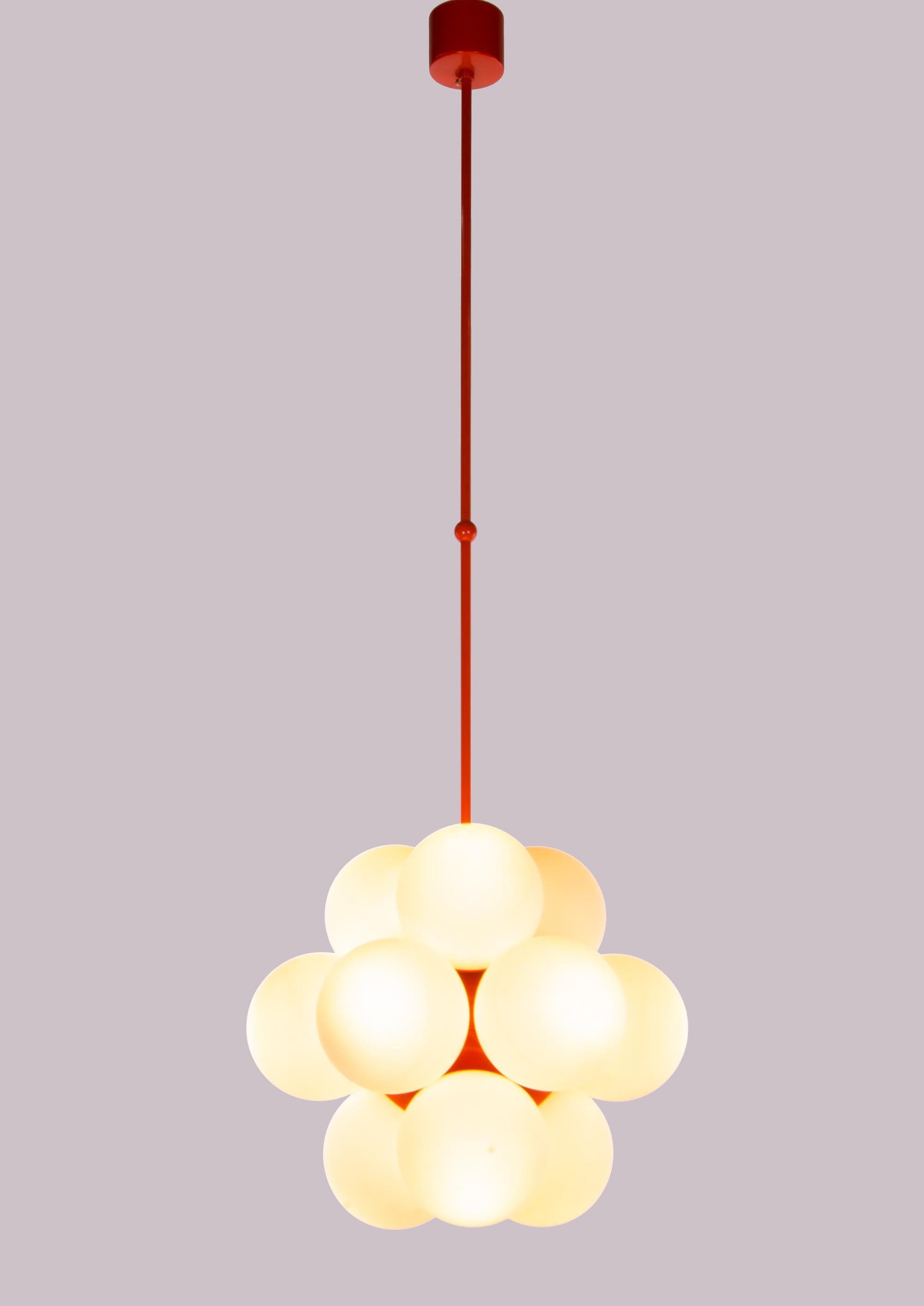 This gorgeous Mid-Century Modernist chandelier with 12 handcrafted double layer opal glass globes on an orange laquered brass frame. Designed and manufactured by Kaiser Lighting, Germany in the 1970s. 
 
Materials: glass and brass. 
Colors: orange,