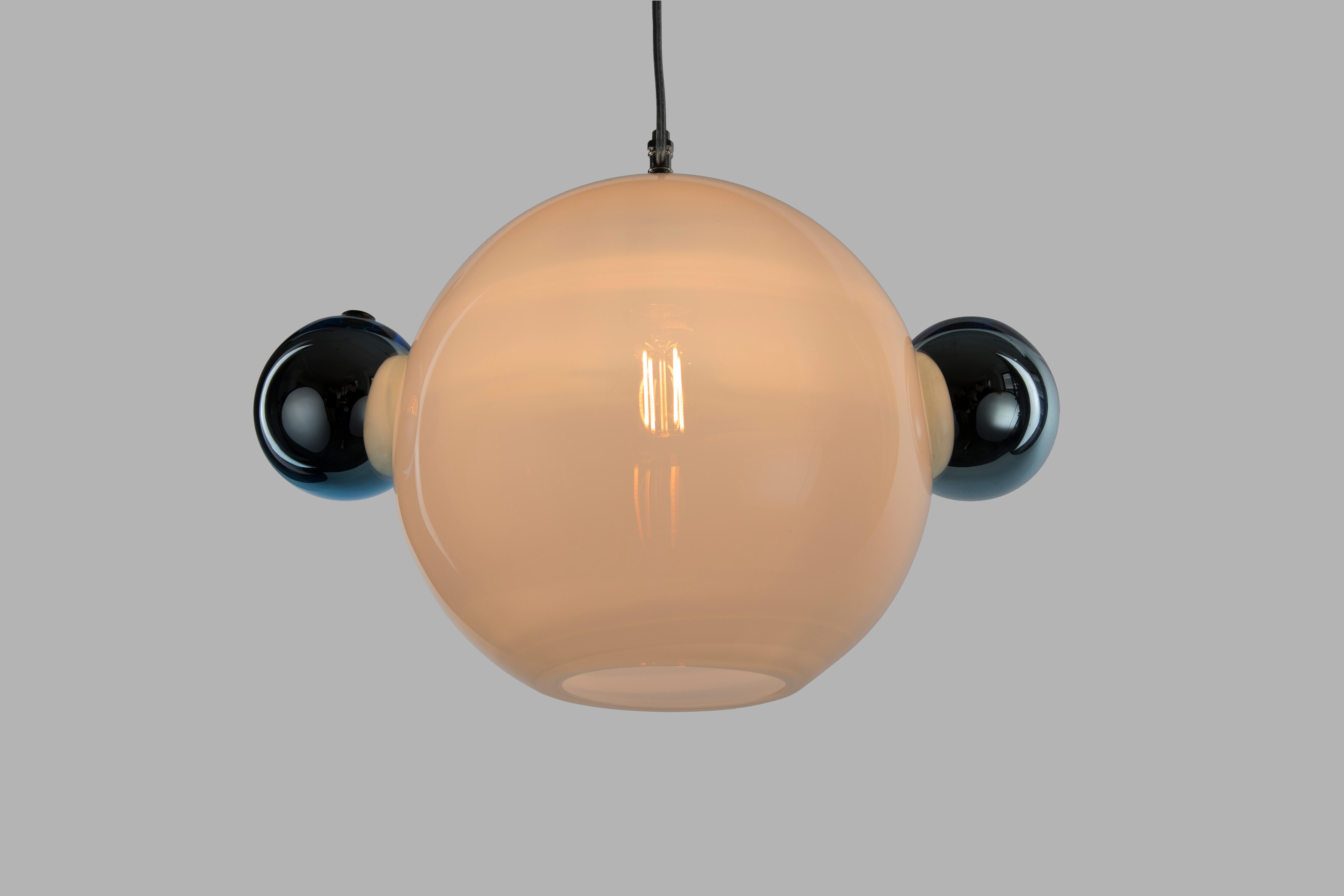 Le pendentif Molecule - Double est un arrangement calculé d'orbes en verre soufflé à la main, destiné à ressembler à une simple structure moléculaire. Il se compose d'une sphère principale opaline de 12