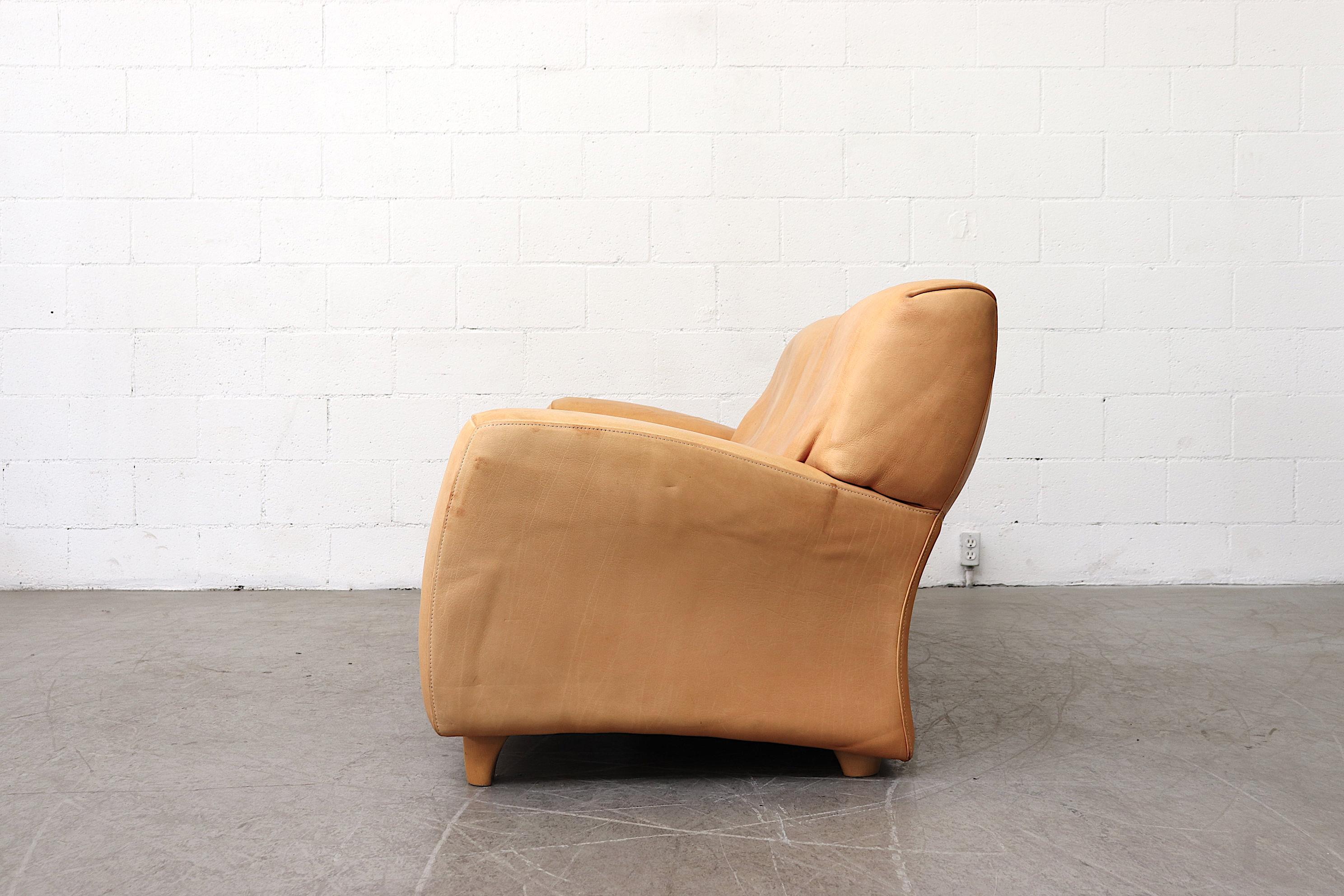 Gorgeous natural leather love seat with beautiful patina. Well maintained stitching details and elegant curves throughout. Original condition with slight staining. Beautiful and comfortable.