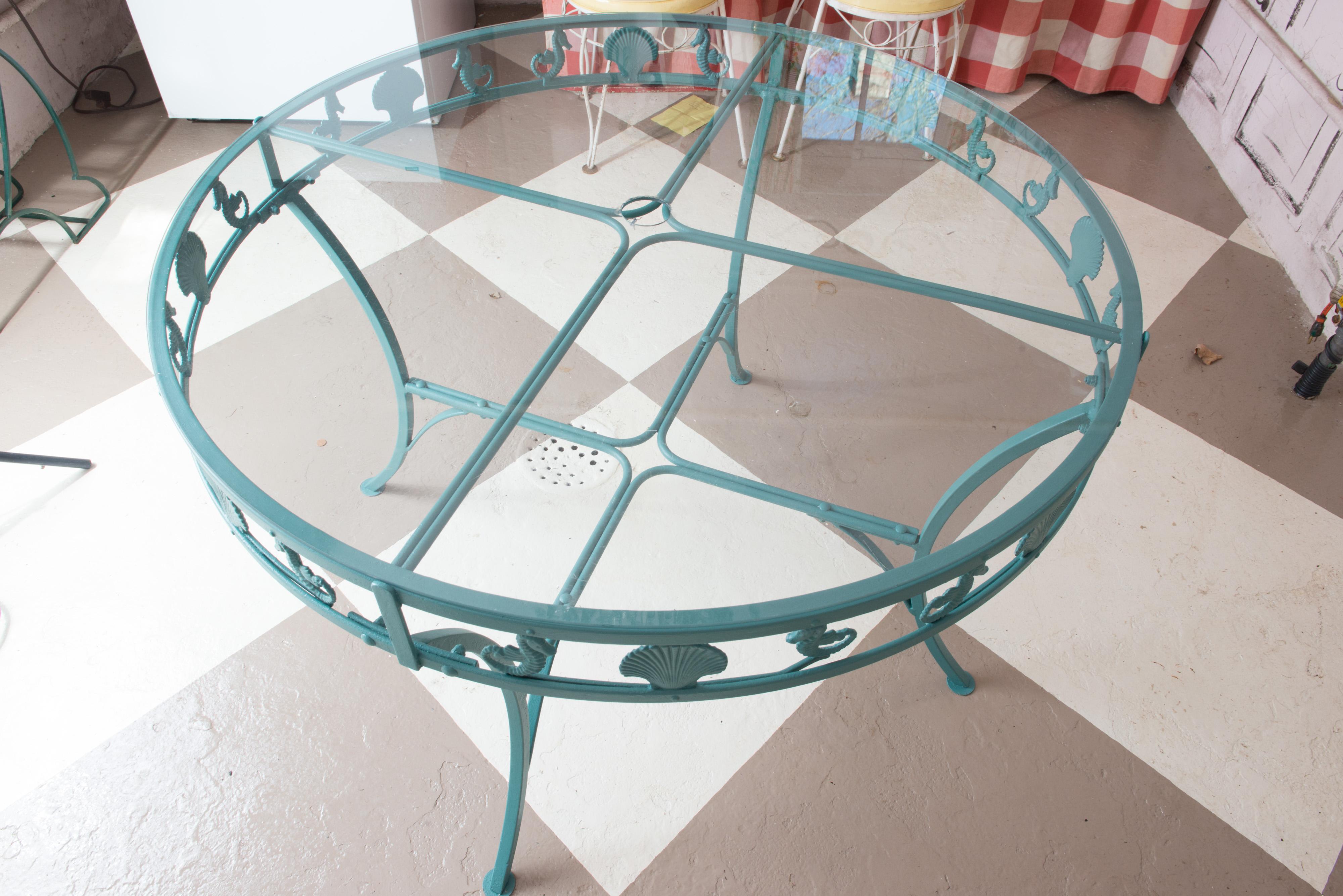 Unusual mid-century Molla round aluminum, glass top garden table with clam shells and seahorses adorning the apron. Painted cast aluminum table with curved legs ending in round feet.
  