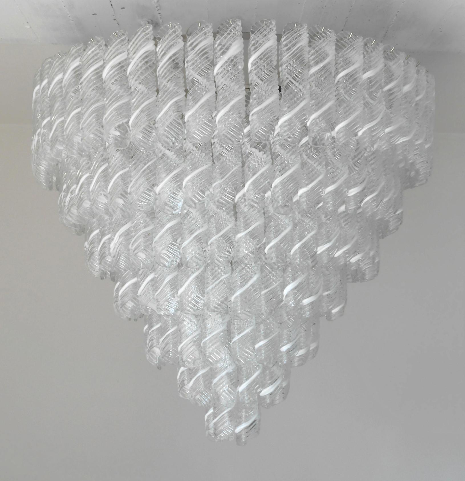 Lampadario italiano con vetri di Murano a righe bianche e trasparenti soffiati a mano per produrre eleganti volute, montati su una montatura con finitura cromata / Made in Italy
21 luci / tipo E26 o E27 / max 60W ciascuna
Misure: Diametro 43,5