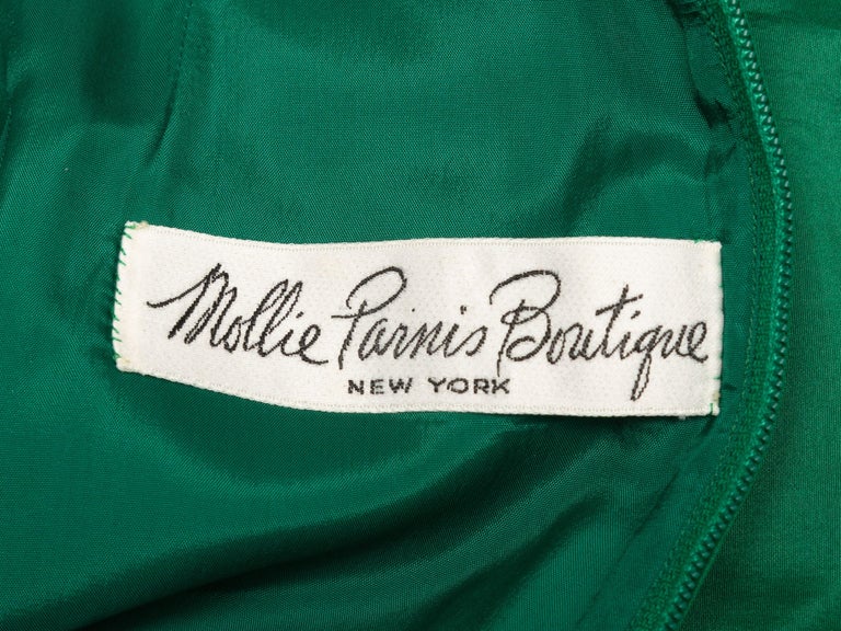 Product Details: Emerald silk taffeta wrap maxi dress by Mollie Parnis. Circa 1970s. Ruffle trim throughout. Long sleeves. Surplice neckline. Tie at waist. Zip closure at back. 34