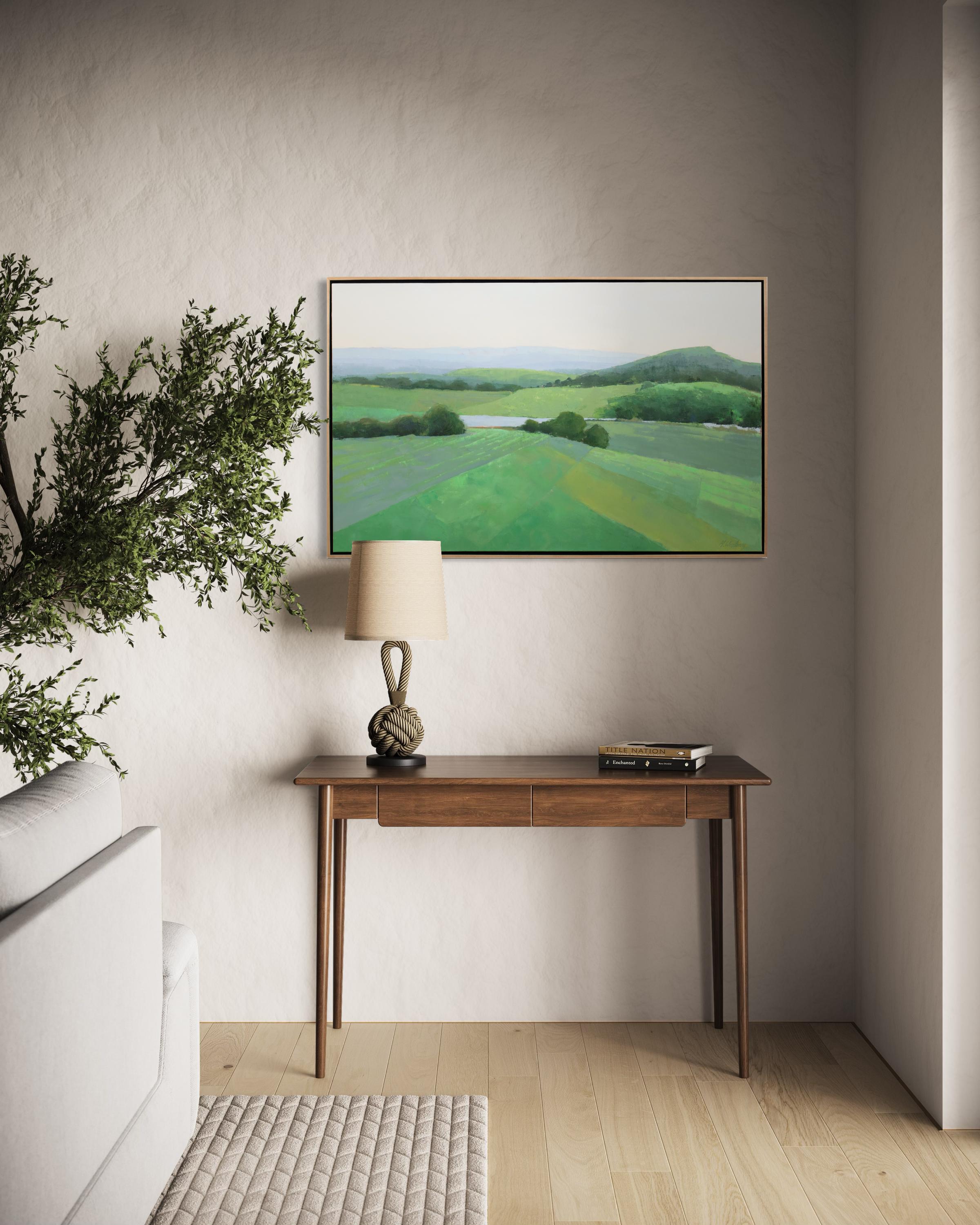 This traditional landscape painting by Molly Doe Wensberg features a cool palette, and captures a scene of lush green, rolling hills under a pale sky. It is very mildly abstracted, with the artist breaking down the scene into planes of varying
