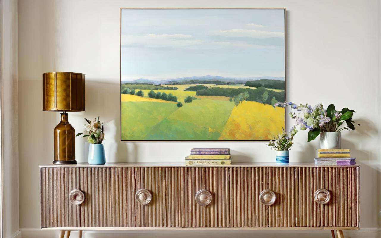 This traditional landscape painting by Molly Doe Wensberg features a cool palette, capturing a scene of lush yellow and green rolling hills under a pale blue sky. It has a mildly abstracted style, with the artist breaking down the hillsides into
