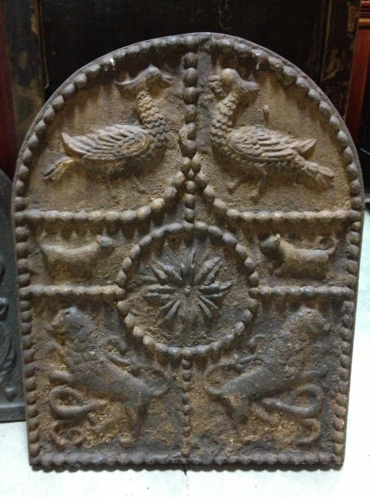 Cast iron fireplace plate decorated with a series of reliefs arranged within strips of pearls and following a symmetrical composition around a central floral motif. The animals (birds, quadrupeds and lions) facing and facing each other (the lions)