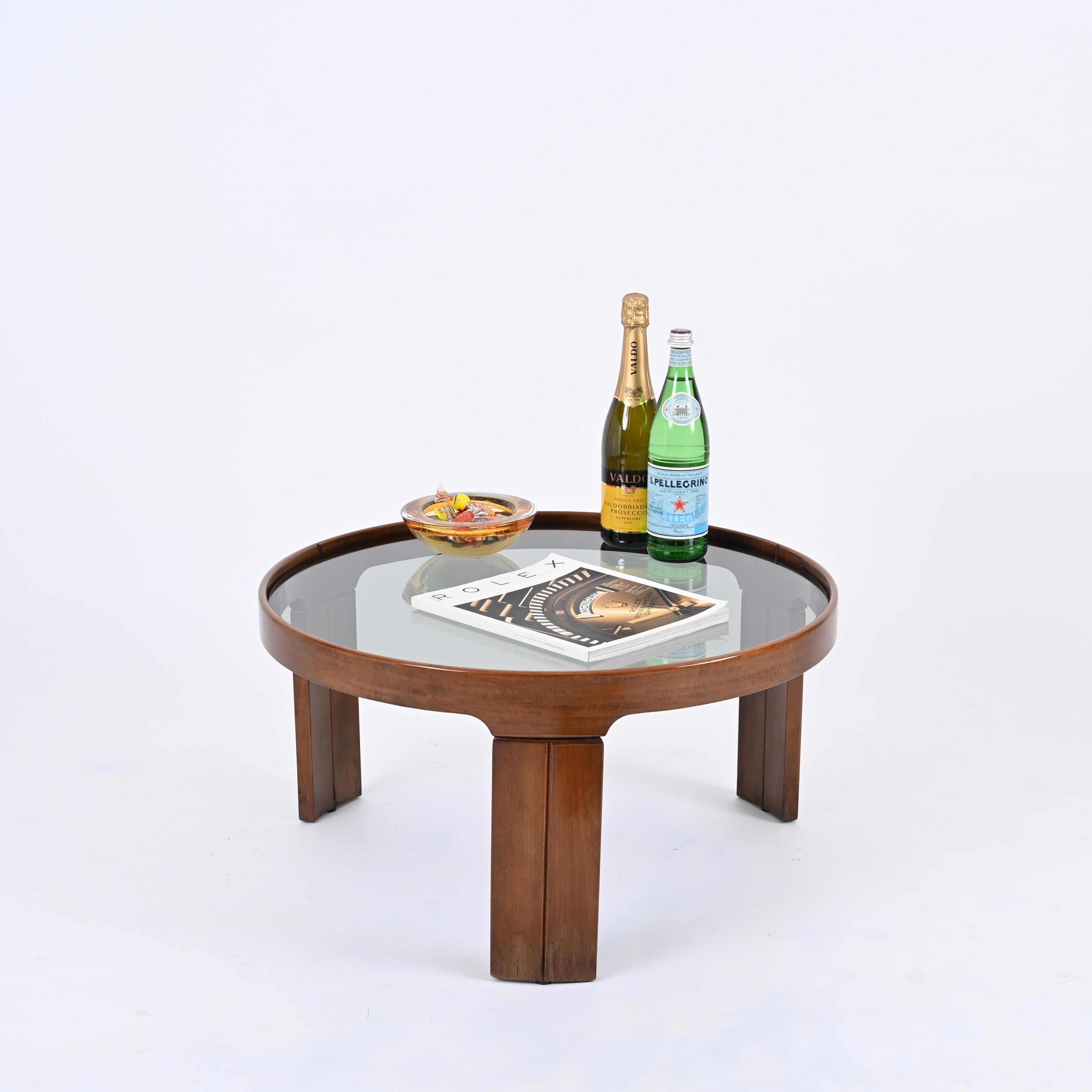 Gorgeous mid-century round tripod coffee table with smoked glass top. This stunning piece was produced by Molteni in Italy in the 1960s.  

Fully made in walnut, this side table features and incredibly elegant design, with three sturdy legs