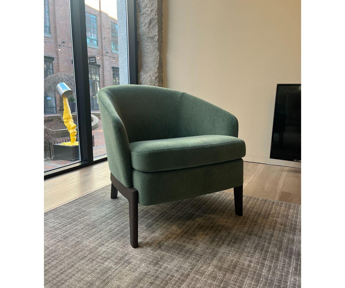 The Chelsea is a small contemporary armchair by Rodolfo Dordoni crafted from solid Black Oak wood with soft green velvet for a stylish and sober design. Featuring seamless armrests and a low seat this streamlined and elegant piece lends itself