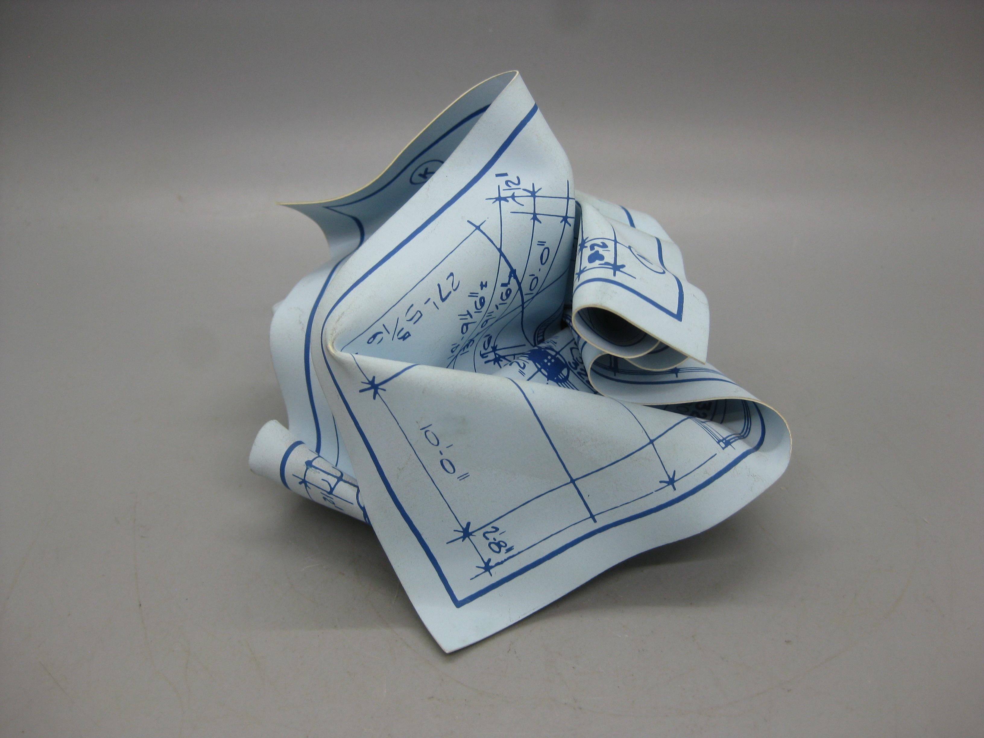 Wonderful three-dimensional art object, which can also be a practical desktop paperweight, was designed by Tibor Kalman. It's made of rigid silk-screened vinyl featuring a replica of an architectural drawing, hand-crumpled, and wrapped around a