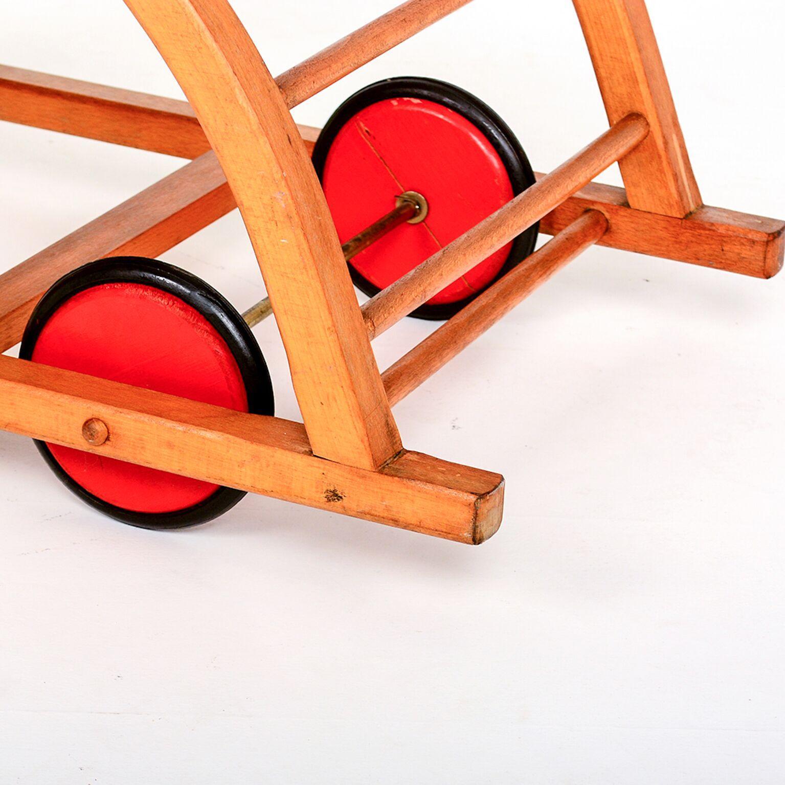 For your consideration a beautiful Mid-Century Modern Schaukelwagen rocking car toy wagon by Hans Brockhage and Erwin Andra. Made in early 1950s. Iconic midcentury design for kids. Beechwood frame, curved plywood seating and red wooden wheels with