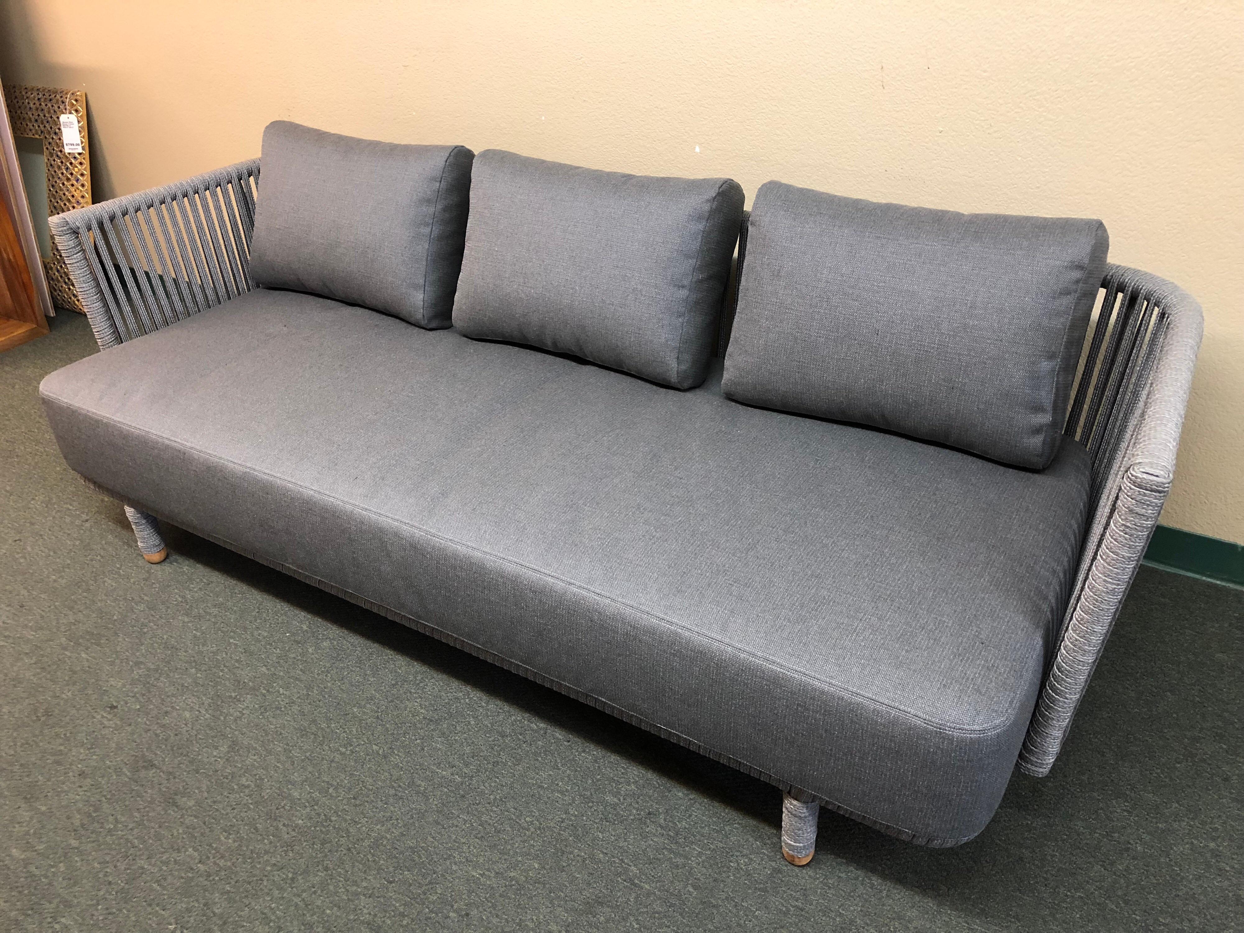A Moments sofa by Cane-tine. This unique design includes a frame made of a weatherproof synthetic material that feels like rope, in a multihued gray. The comfy bench cushion and loose cushions come in a coordinating grey soft touch fabric, with