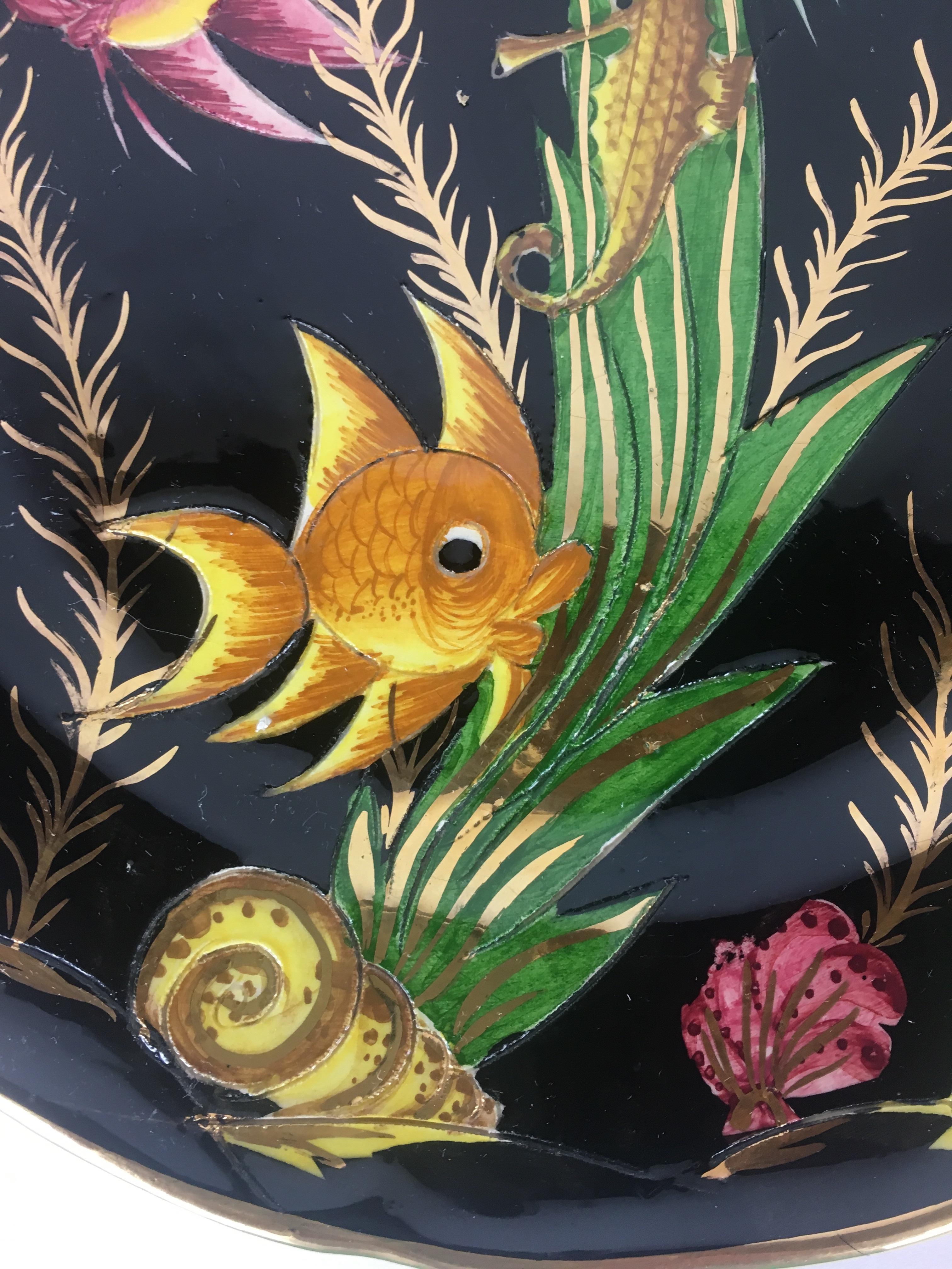 A whimsical pair of ceramic D'Art Lamarche from Monaco glazed ceramic wall plates. Both of these decorative plates have a black background and a colorful trompe l'oeil decoration composed of fishes, and sea plants. These pieces would make wonderful