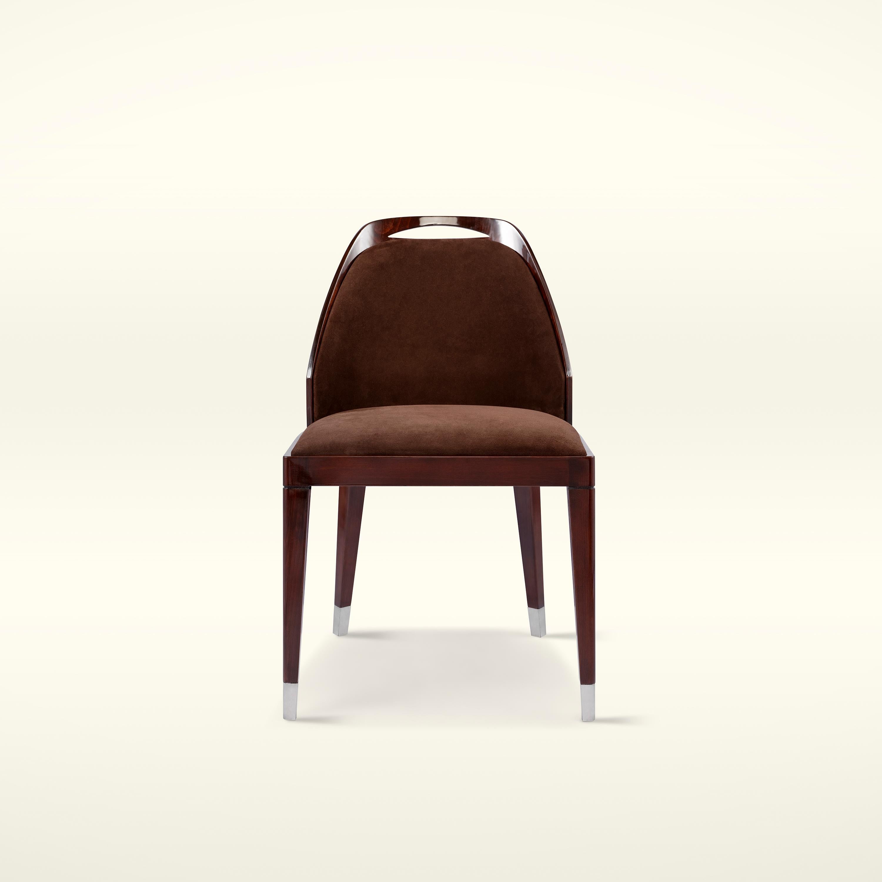 La Monaco Chair, ispirata all'eleganza di Grace Kelly, avvolge il corpo, richiamando il glamour di quell'epoca con la sua scocca laccata lucida e fornendo un tocco caldo con l'imbottitura in nabuk. Le sue gambe in acciaio inossidabile forniscono