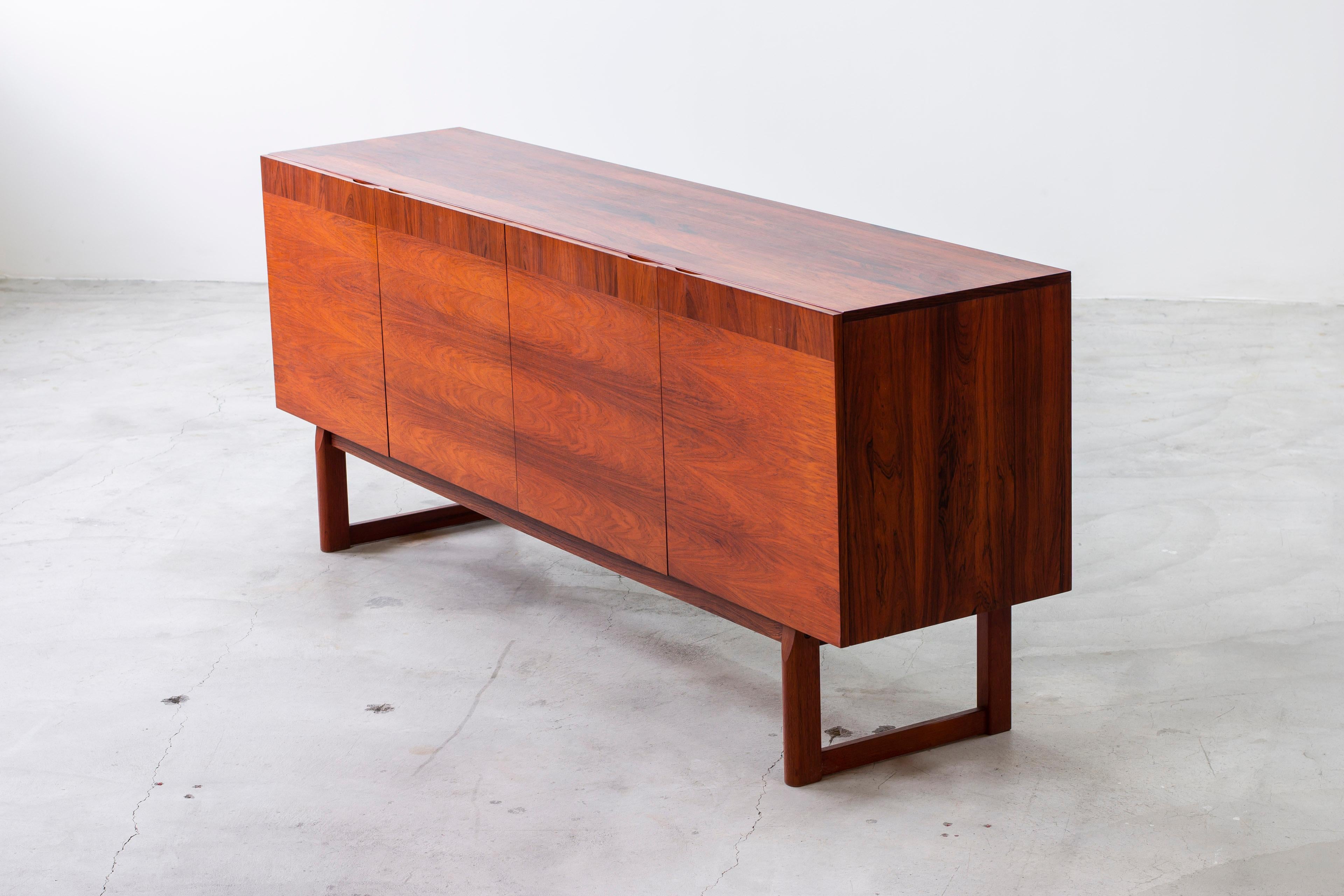 Sideboard model Monaco designed by Nils Jonsson. Produced by Hugo Troeds in Sweden during the 1960s. Exterior in palisander wood and interior in contrasting light oak and white lacquered details. The shelves are optional and can be adjusted in
