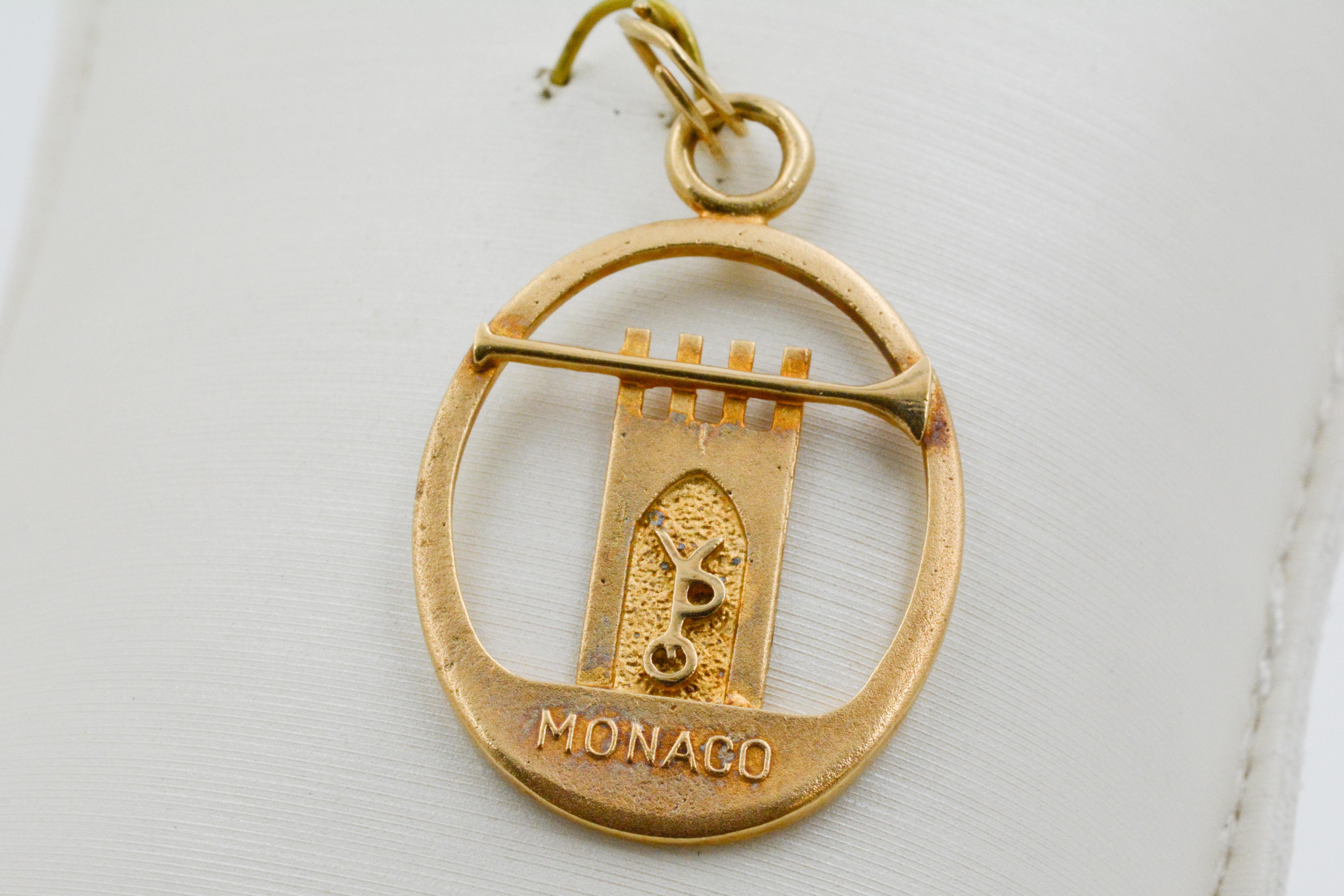 This regal charm is fashioned from 14kt yellow gold and features a cutout of a castle image with the letters “YPO” embossed on the doorway. A long trumpet plays across the top, and the word “Monaco” is embossed at the bottom. The back of the charm