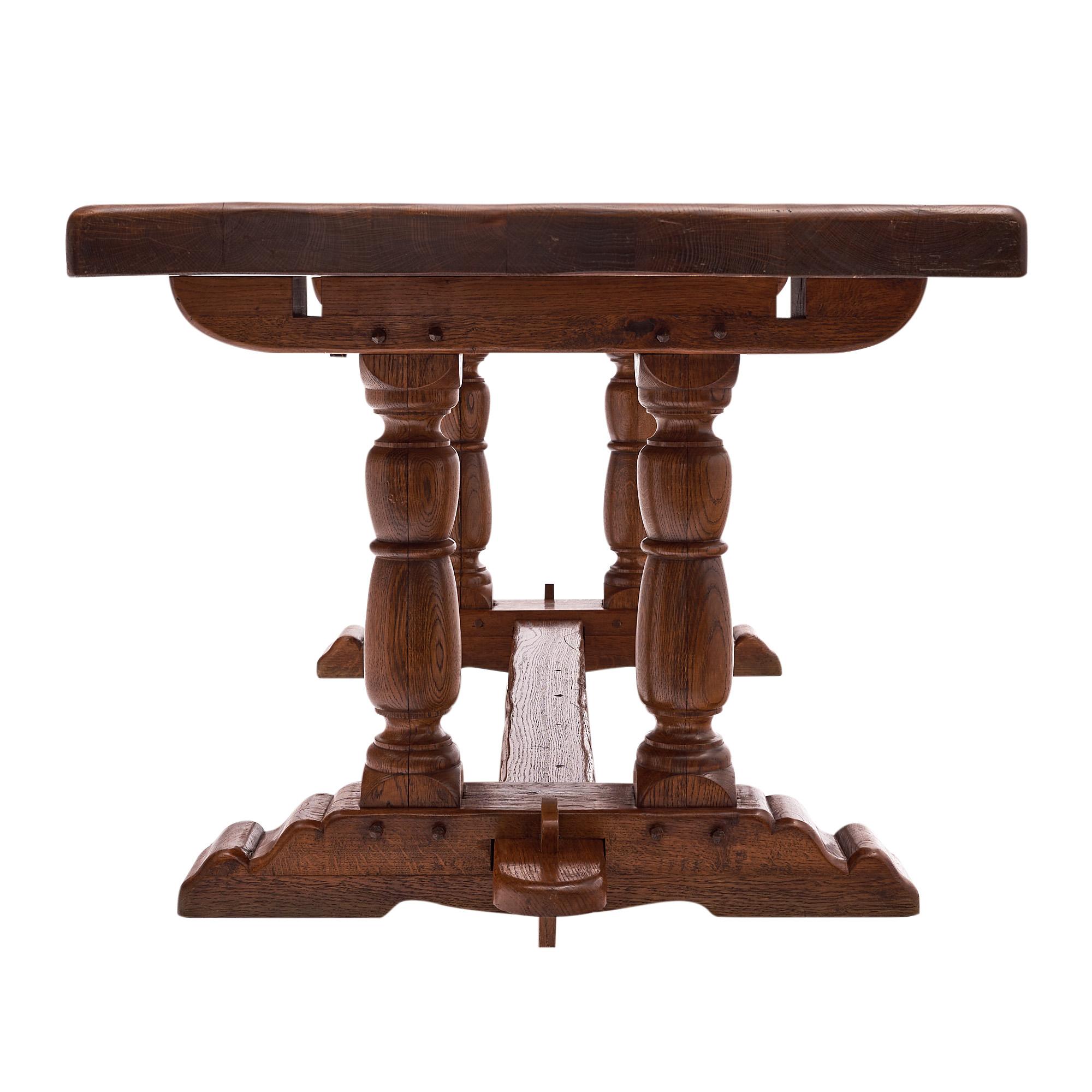 Dining table from France made of solid oak. This piece has a base with double column pedestals and peg construction throughout. It has been finished with wax and the top is 3.75” thick.