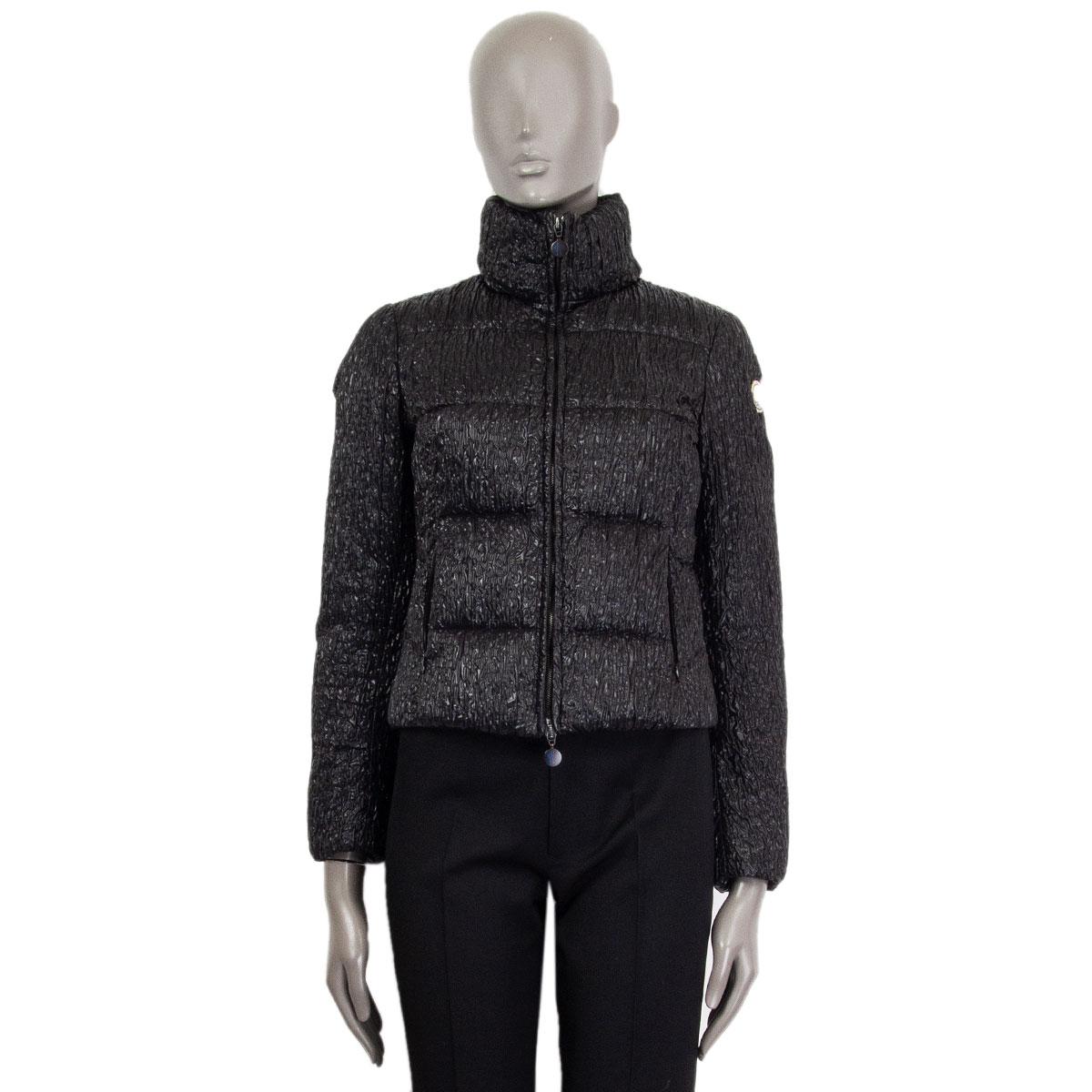 100% authentic Moncler quilted down-jacket in black polyamide (100%) and filling in duvet down (100%) with high collar and brand-logo on the left upper-arm. Closes with a black logo embossed zipper on the front and with zipped slit pockets. Lined in