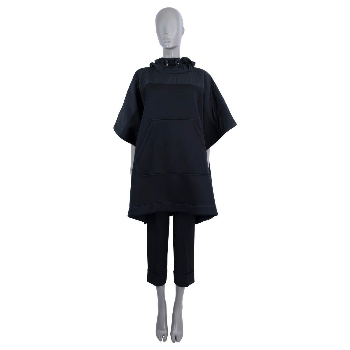 100% authentischer Moncler Poncho mit Kapuze und kurzen Ärmeln aus schwarzem Polyester (100%). Mit Moncler-Schriftzug auf der Rückseite und Taschen auf der Vorderseite. Schließt mit Druckknöpfen an der Seite. Unbeschriftet. Wurde getragen und ist in