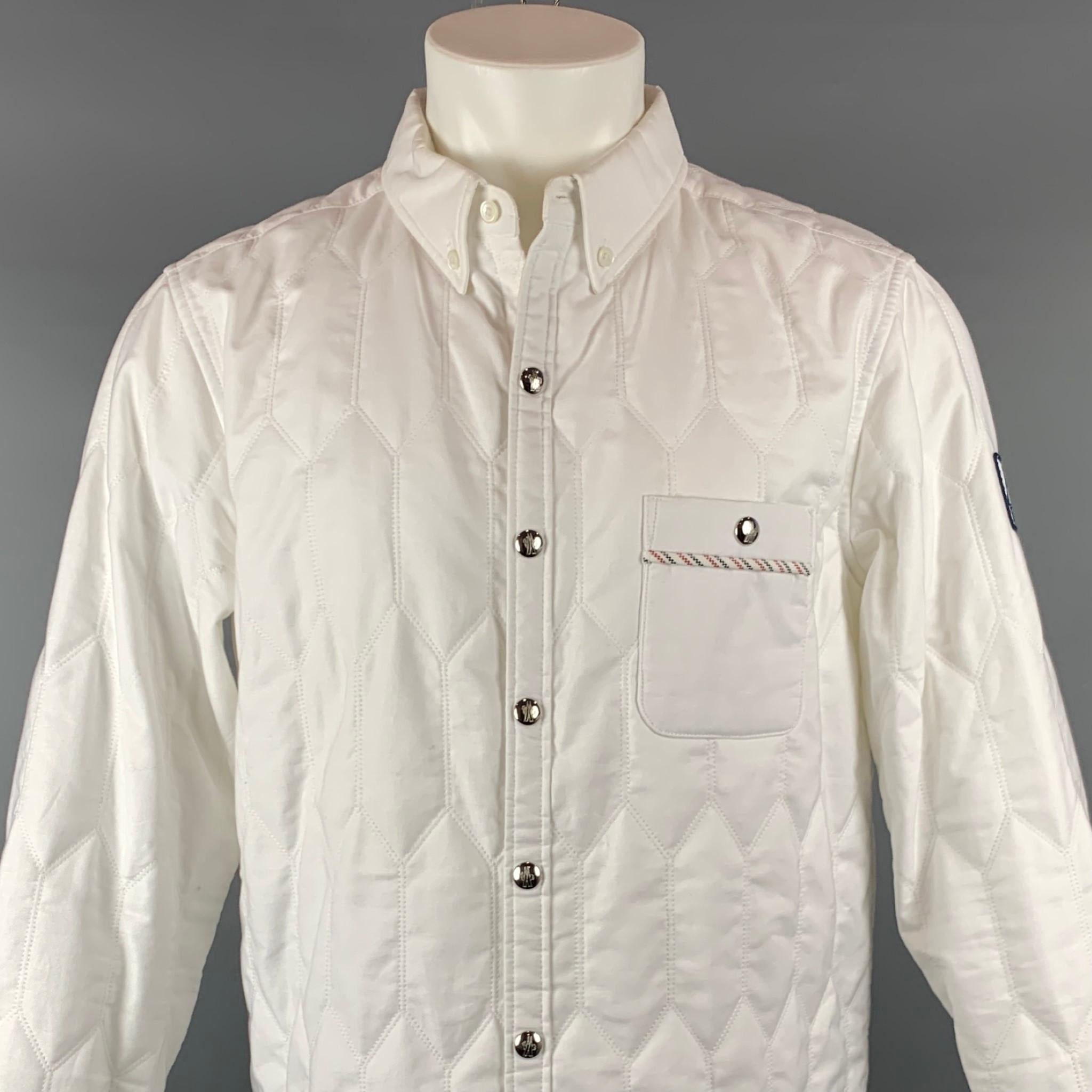 MONCLER GAMME BLEU long sleeve shirt comes in a white quilted cotton featuring a button down collar, sleeve logo detail, striped trim, front pocket, and a snap button closure. Made in Italy.

Very Good Pre-Owned Condition.
Marked: