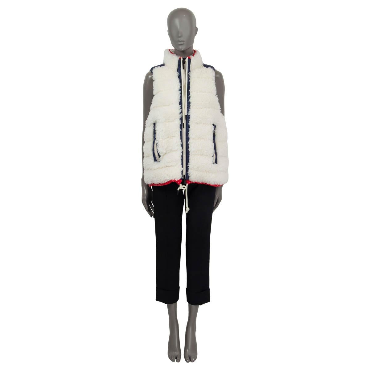 100% authentic Moncler Grenoble shearling padded down vest in white, blue and red polyester (100%). Featres two zip pockets on the front and drawstring closures at the neck and the hips. Opens with a zipper on the front. Lined in navy blue polyamide