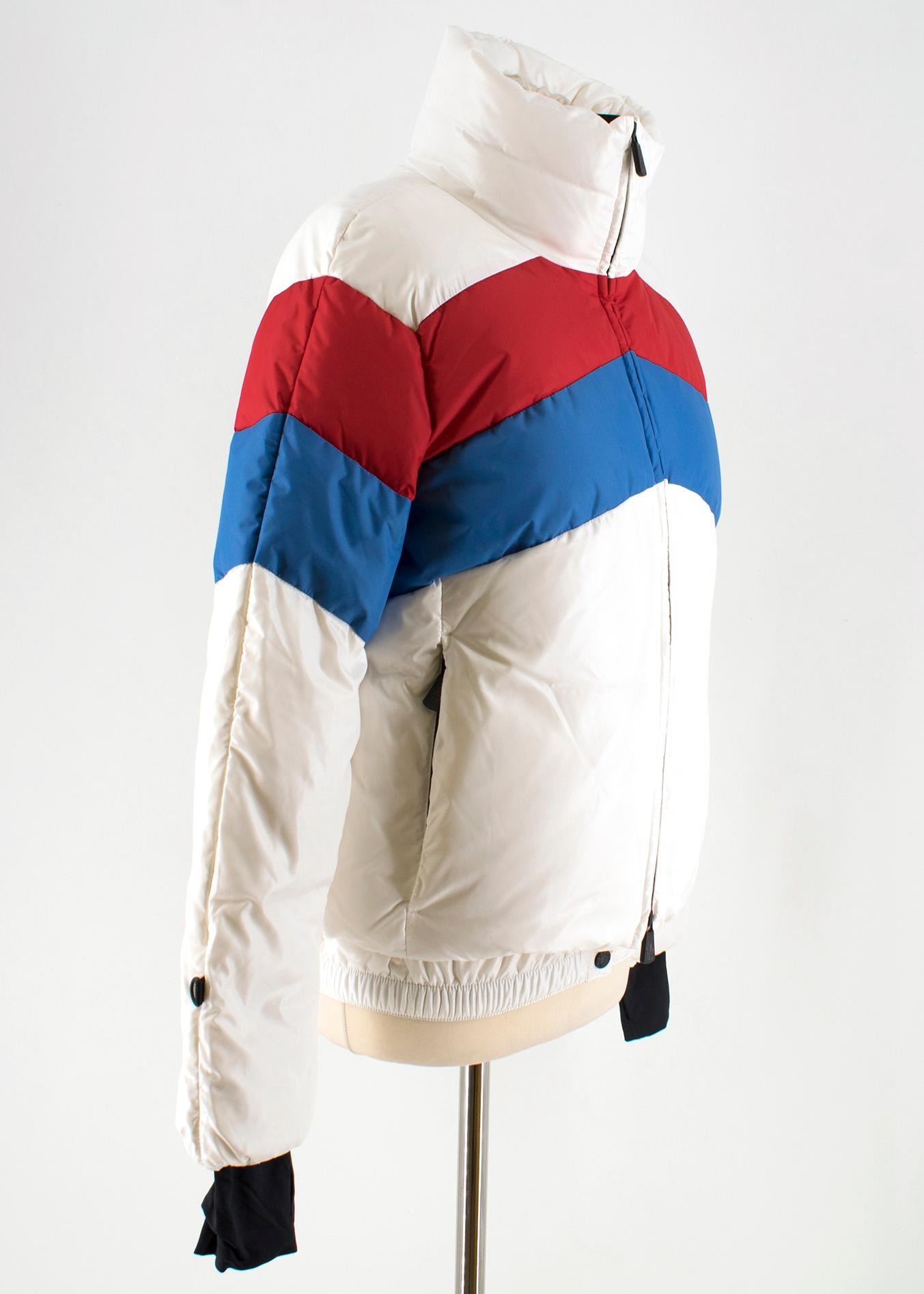Moncler Lamar down-filled ski jacket

- White, high-shine nylon 
- Down and feather filled
- High neck, long sleeves 
- extended black jersey cuffs, thumbhole slits 
- Navy and red quilted striped yoke and sleeves
- Logo embroidered felt sleeve