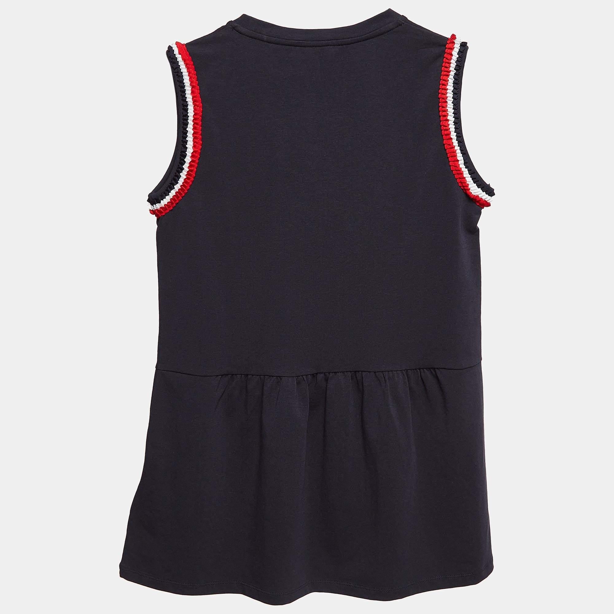 Este top sin mangas de Moncler diseñado para niños presenta un elegante tono azul marino y un estiloso diseño de punto con volantes. Fabricado en algodón de alta calidad, ofrece un ajuste cómodo y a la moda. Los juguetones detalles de volantes le