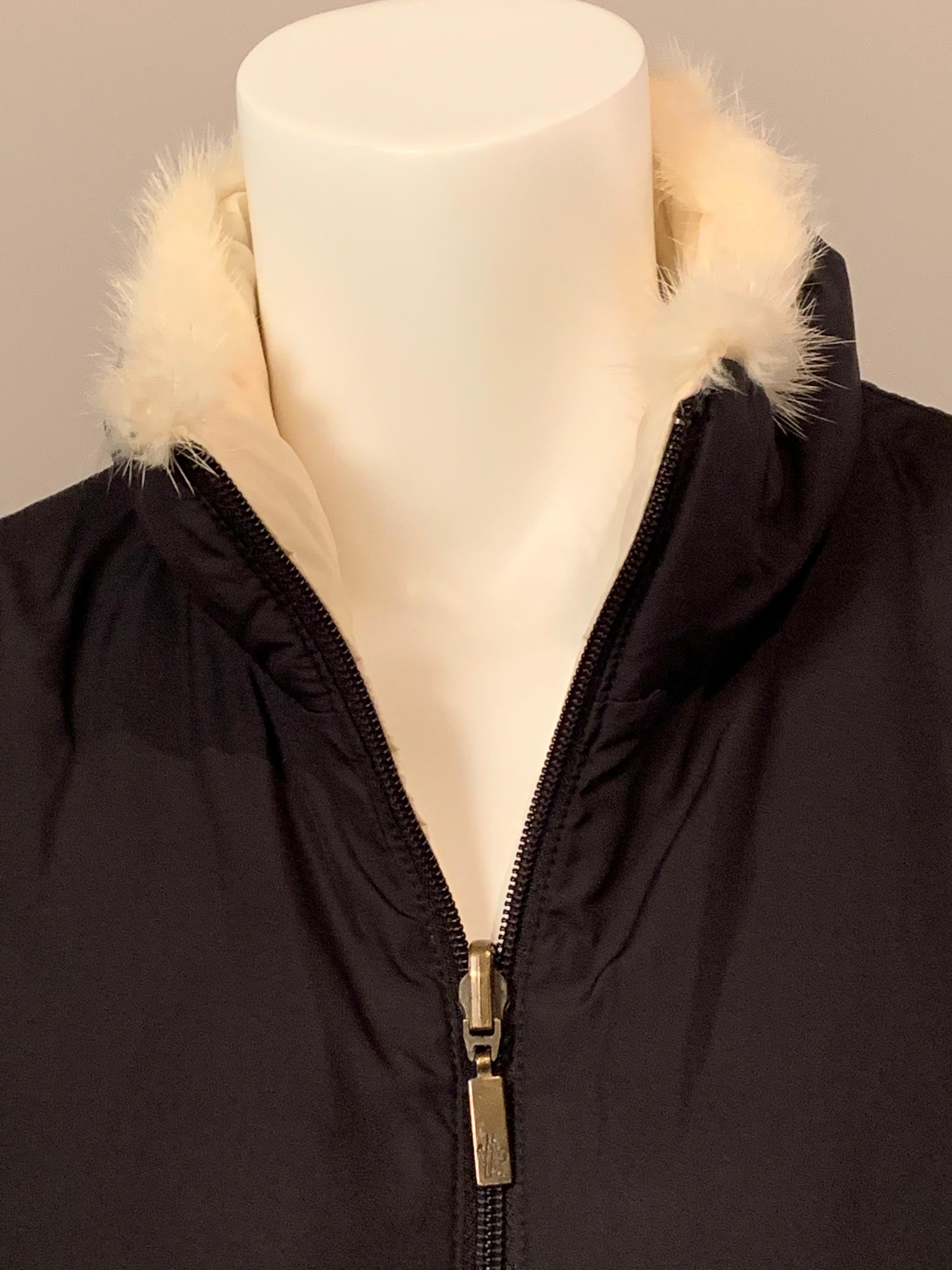 Made in Switzerland by Moncler, this down filled vest has a stand up collar, center front zipper, side pockets with invisible zippers and a small label on the side.  There is a larger label in a pocket.  It is black, reversing to creamy white, with