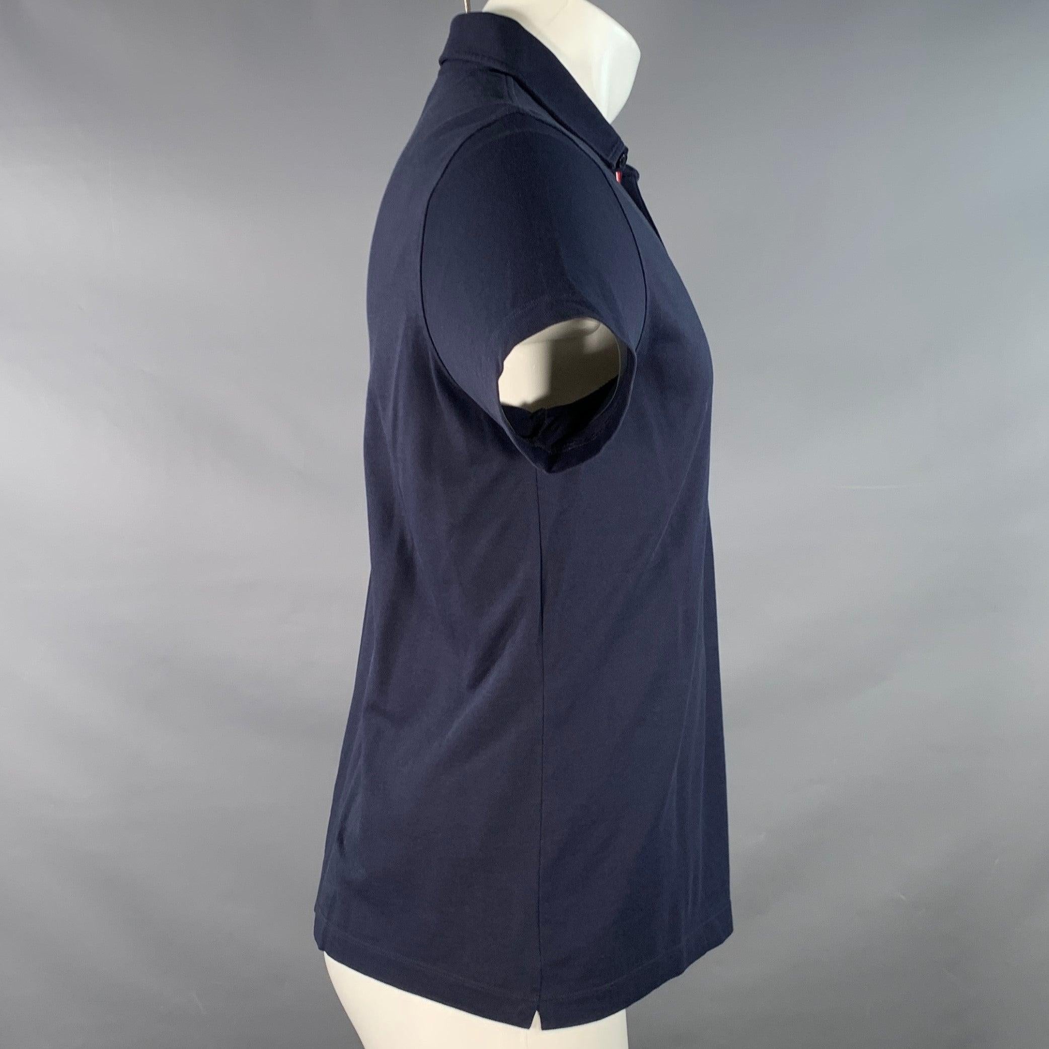 MONCLER polo
en piqué de mezcla de algodón azul marino con ribete de rayas características, un bolsillo y media tapeta abotonada. Excelente estado de conservación. 

Marcado:   M 

Medidas: 
 
Hombro 16 pulgadas Pecho: 39 pulgadas Manga: 7 pulgadas