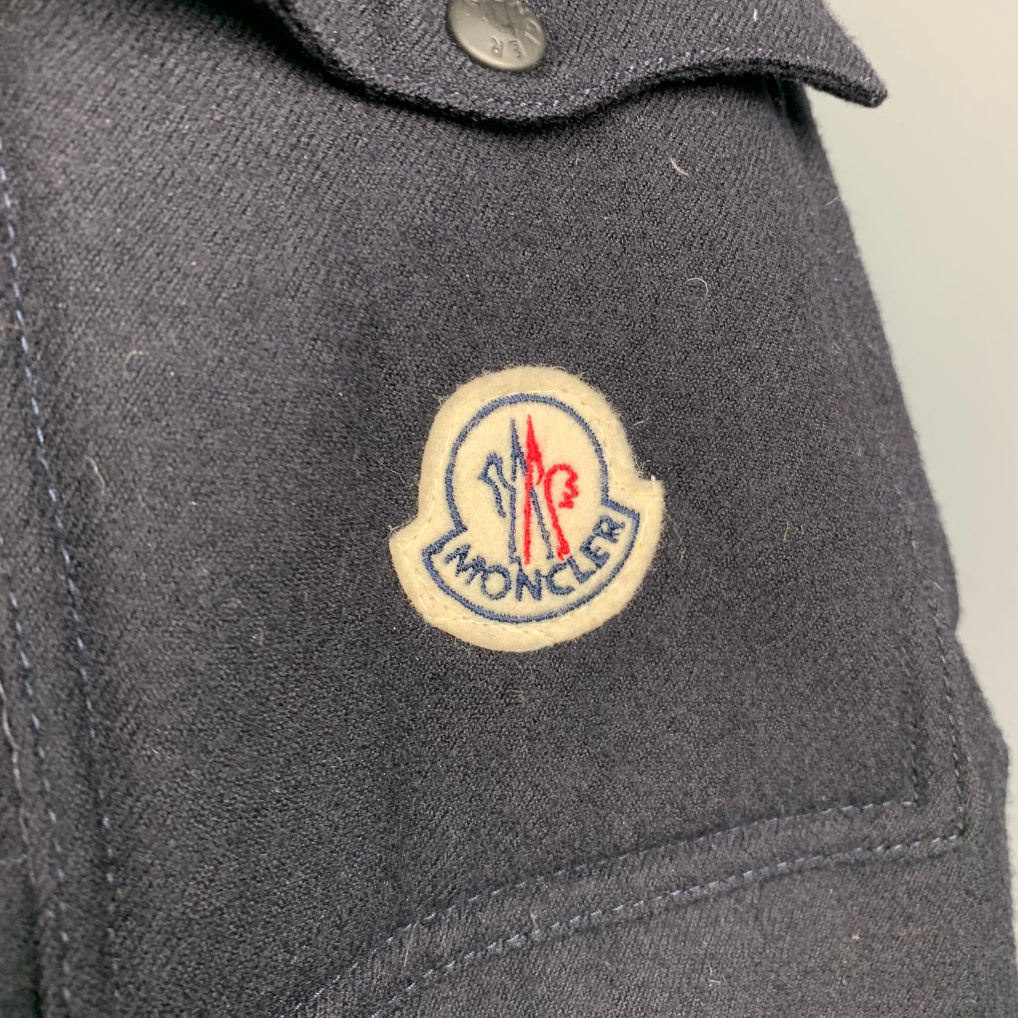 MONCLER parka comes in a navy quilted wool, down filled featuring featuring a hooded style with a removable fur trim, front pockets, and a zip & signature Moncler button closure. Mino wear. Made in Italy.

Very Good Pre-Owned Condition.
Marked:
