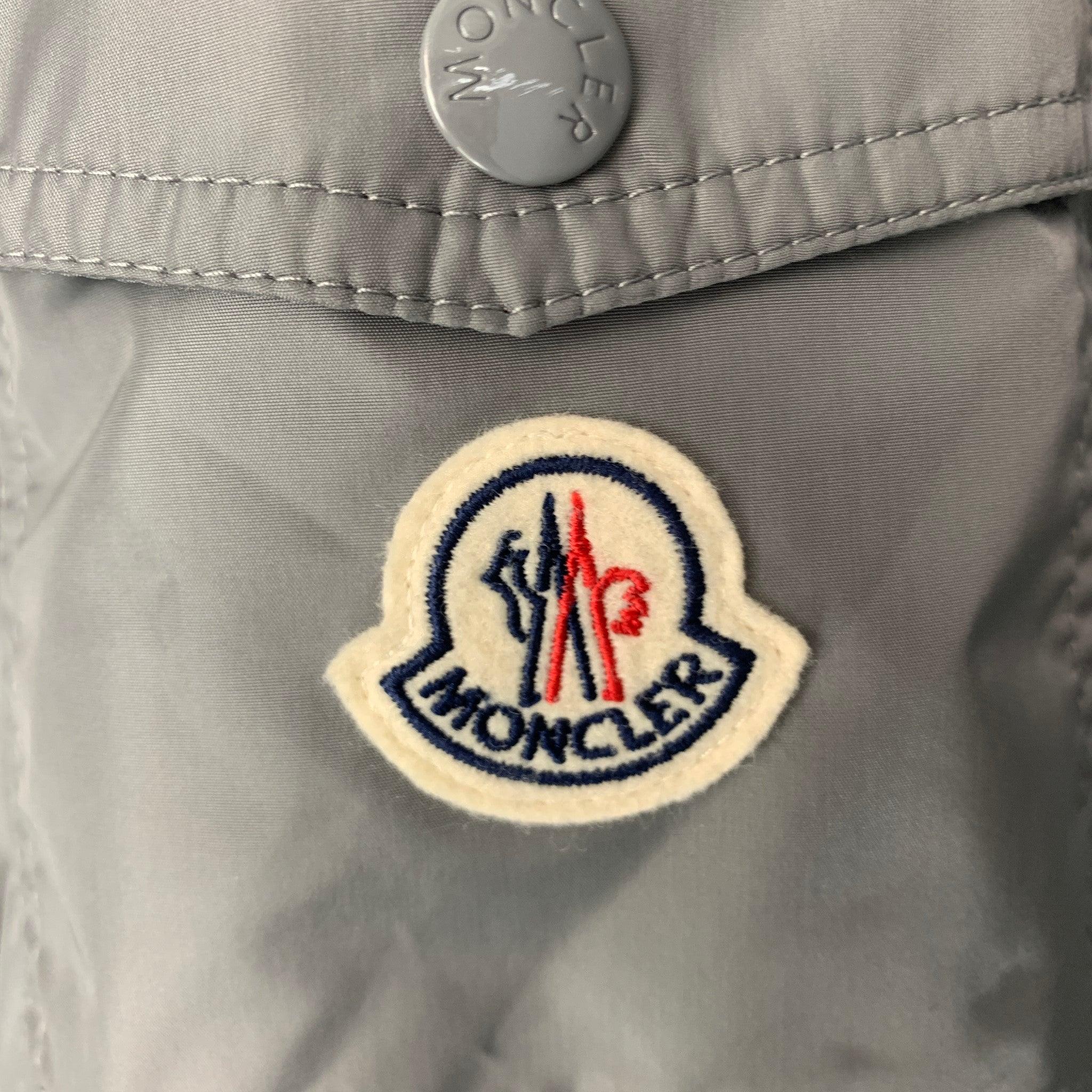 MONCLER windbreaker jacket comes in grey nylon woven material featuring a hidden hood, elastic cuffs, zipper pockets, and zip up closure. Very Good Pre-Owned Condition. Minor signs of wear. 

Marked:   7 

Measurements: 
 
Shoulder: 20.5 inches