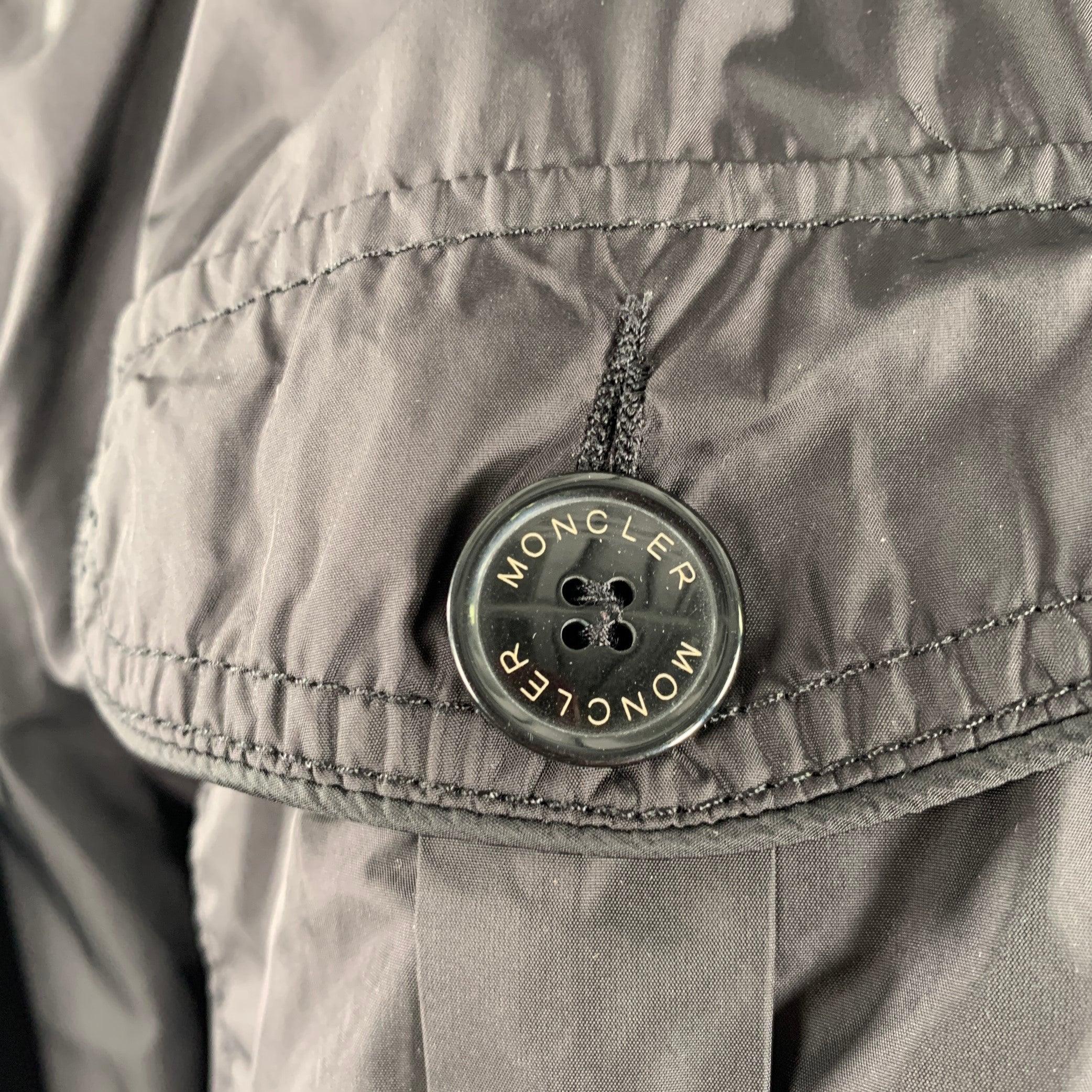 MONCLER jacket
in a black polyamide fabric featuring four large buttoned pockets, contrasting black and white striped rib knit collar, and a zip up & hidden button closure.Excellent Pre-Owned Condition. 

Marked:   6 

Measurements: 
 
Shoulder: