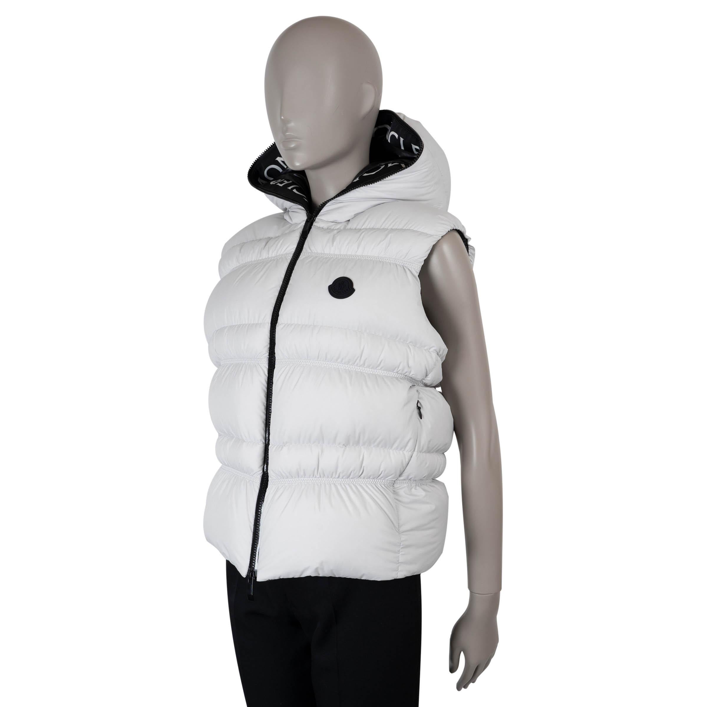 Questo gilet Moncler Weser, autentico al 100%, è realizzato in poliestere trapuntato bianco ghiaccio per un look elegante e moderno. Progettato con una silhouette aderente e aderente, presenta un cappuccio per una maggiore funzionalità e due tasche