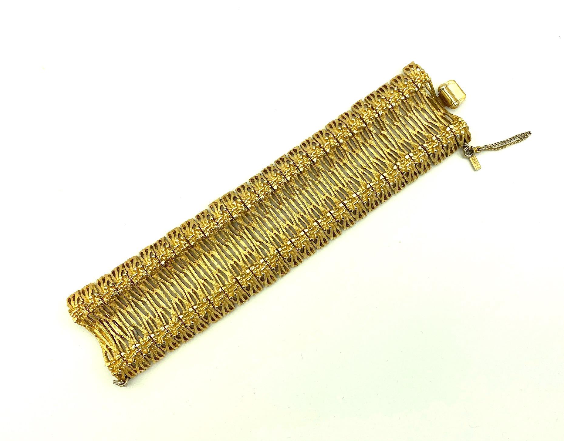 Monet 1960s wide satin gold plate bracelet comprised of twenty six wide bar links strung on two chains. Each link is narrow measuring a little over a quarter of an inch wide and 1.75 inches long. The links are concave in the center and rounded on