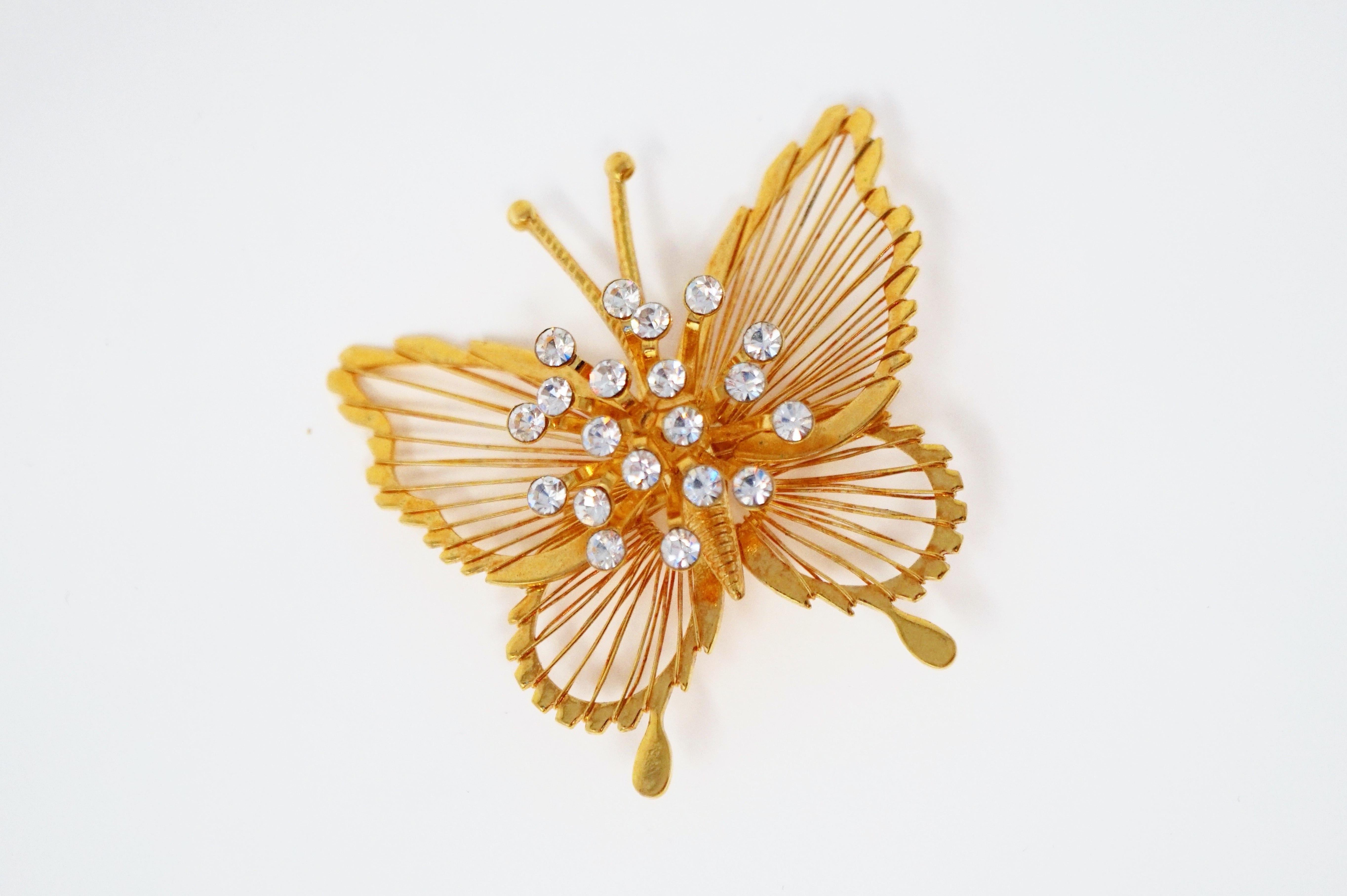 This gorgeous gilt butterfly brooch by Monet, circa 1970s, is a wonderful example of the quality and innovative designs that the coveted vintage costume jewelry brand is known for. With a shiny gold-plated finish and crystal rhinestone spray detail,