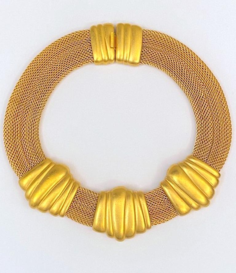 An original and in excellent condition Art Deco revival gold necklace from the 1980s by American fashion jewelry company Monet. The gold plate has a satin finish on the three large cast ornamental pieces in the front and on the matching clasp in the