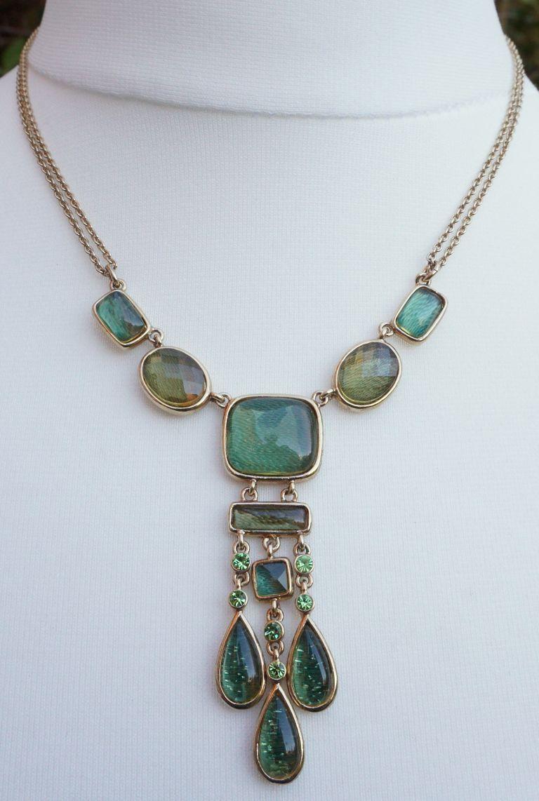 Monet gold plated drop pendant necklace featuring cabochon and faceted resin stones in warm olive green and cool mid green, and green rhinestones. The small square is turquoise green. The resin stones have an attractive background pattern. There is