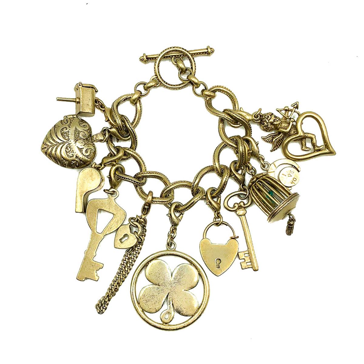 A stand out Vintage Monet Charm Bracelet. Created to celebrate Monet Jewelry's 75th anniversary. Crafted in a very mellow, antiqued gold plated metal. Featuring a myriad of charms, eleven in total, including many denoting good luck and romance and