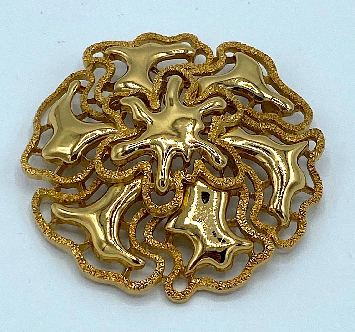 A lovely brooch from the 1974 Mandira collection by well known American fashion jewelry company Monet. It features a polished and textures gold plate finish on the abstract design. The brooch is lightly domed measuring 2.5 inches in diameter .5 of