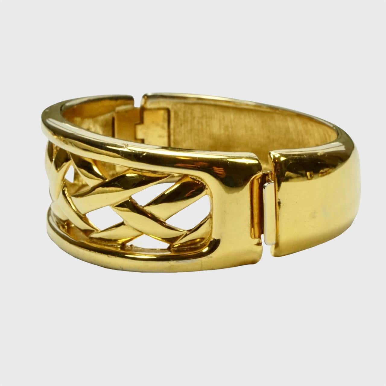 Monet 22ct triple gold plated lattice design bangle with side clasp. Measuring inside diameter approximately 5.8 cm / 2.8 inches by 4.95 cm / 1.9 inches. The width graduates from 1.5 cm / .6 inch at the back to 2.3 cm / .9 inch at the front. The