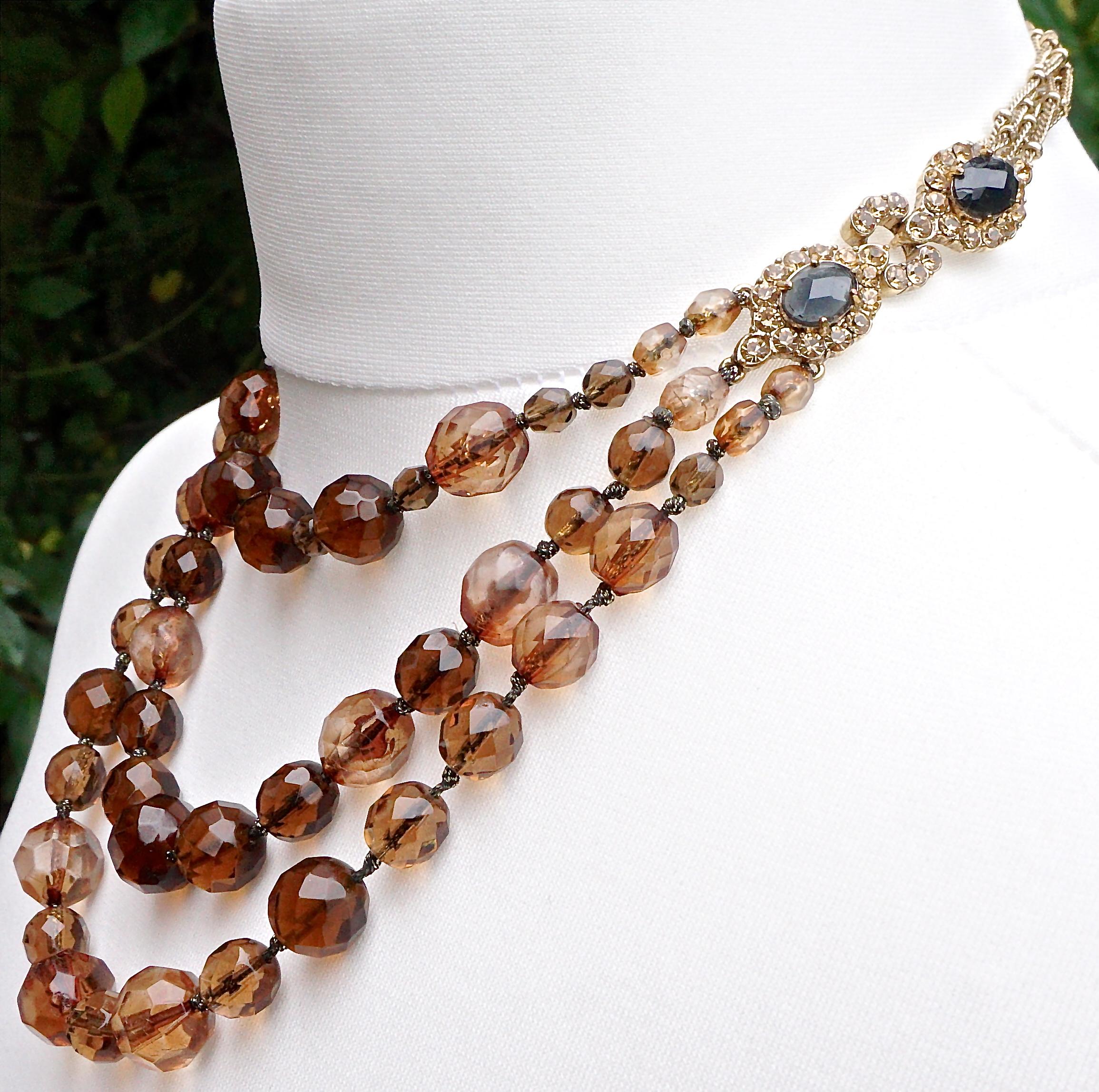 Monet gold plated necklace featuring three strands of faceted glass beads in warm dark brown, warm light brown, and clear / brown. They are strung on silver tone chain, and the chain is knotted between each bead. The strands are connected to