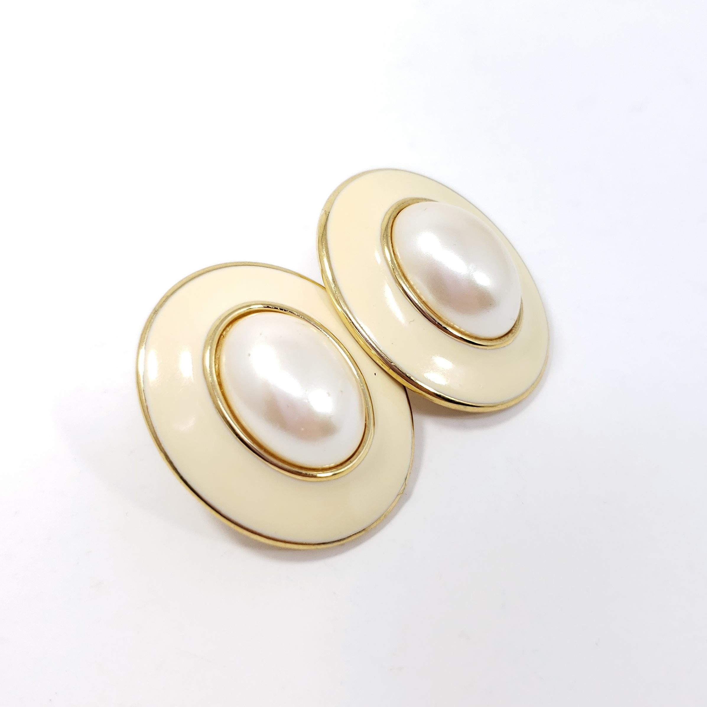 Big and bold, a pair of chunky clip on earrings. Stylish retro flair!

Latte / off white enamel and faux pearl center cabochon. Gold plated.

Late 1900s.

Marks / hallmarks / etc: Monet