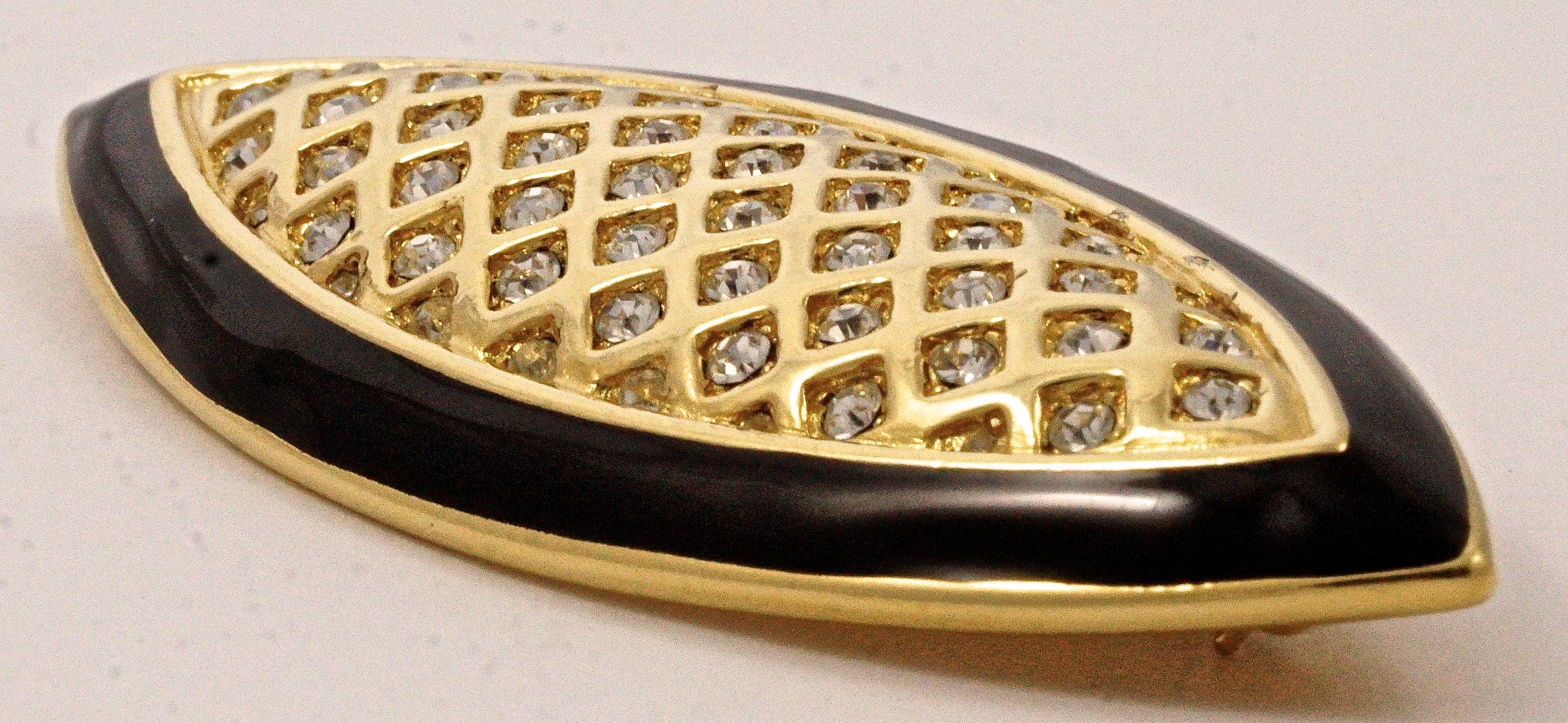 Stylish Monet gold tone brooch featuring rhinestones set in diamond shape latticework with a black enamel edging. Measuring length 7.1cm / 2.79 inches by width 2.7cm / 1.06 inches. The brooch is in very good condition.

This is an elegant and