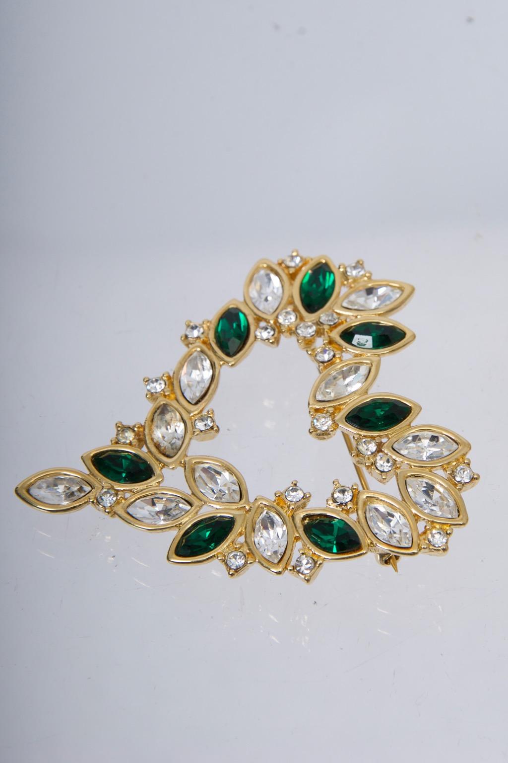 Monet heart-shaped brooch consisting of offset clear marquise crystals interspersed with emerald crystals and accented with small rhinestones, all in a gold metal setting.  Copyright Monet signature bar on reverse.