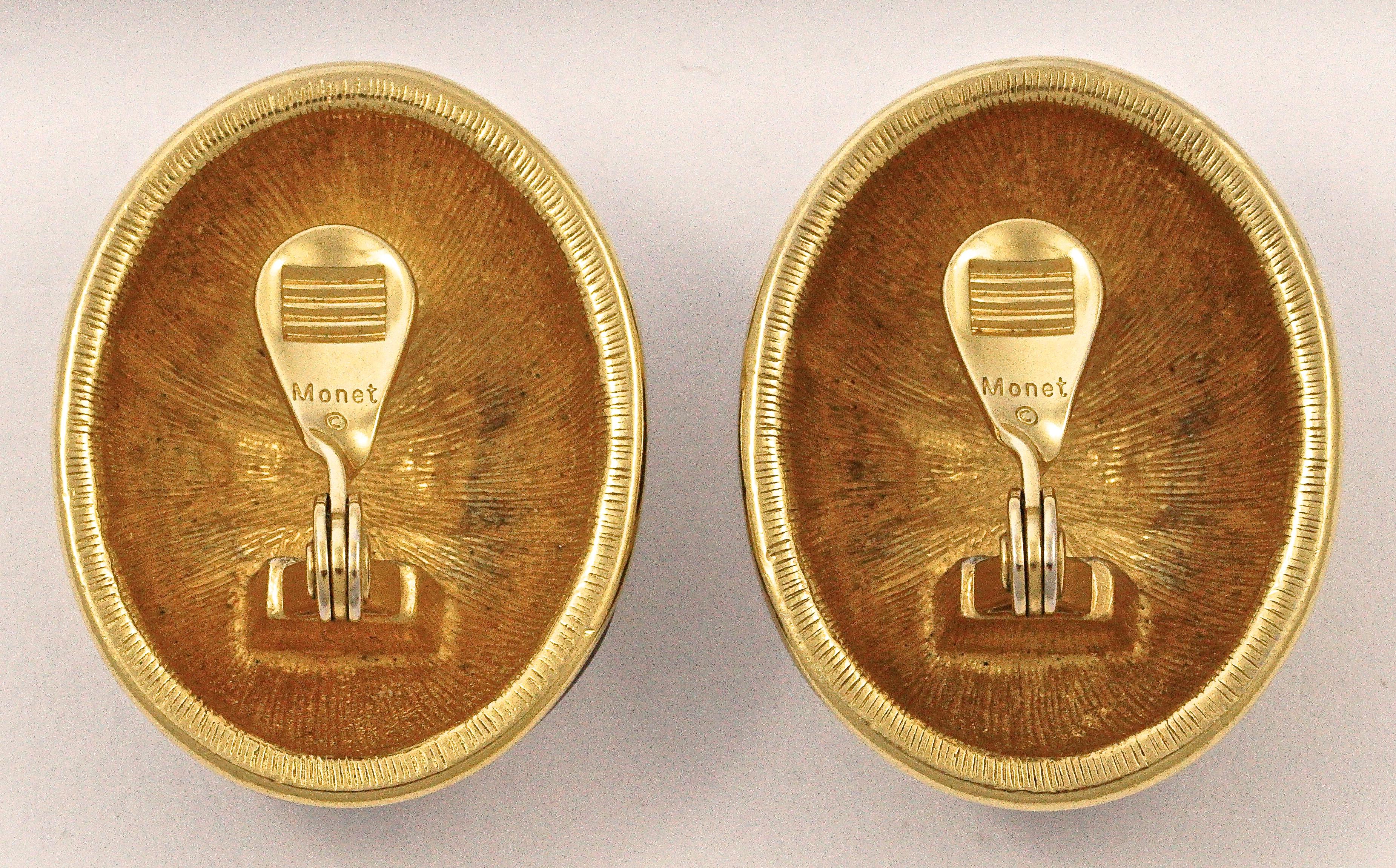 Stylish Monet oval gold tone clip on earrings, featuring curved golden bands on black enamel. The earrings are domed and measure length 3.6cm / 1.41 inches by width 2.8cm / 1.1 inches.

This is an elegant pair of quality vintage Monet earrings,