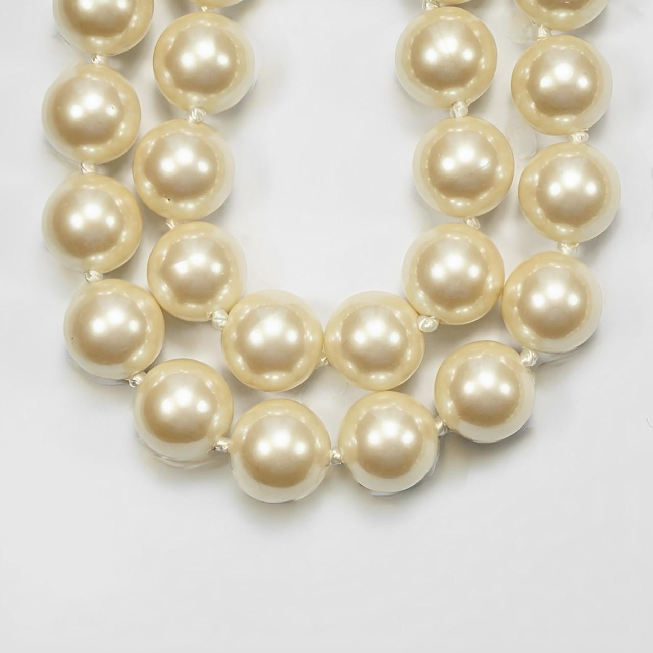 Magnifique collier Monet à deux rangs de fausses perles en verre crème, doté d'un élégant fermoir plaqué or. Les perles lustrées sont nouées entre chaque perle. Le brin le plus court mesure 84,5 cm de long et les perles mesurent 1 cm de long. Le