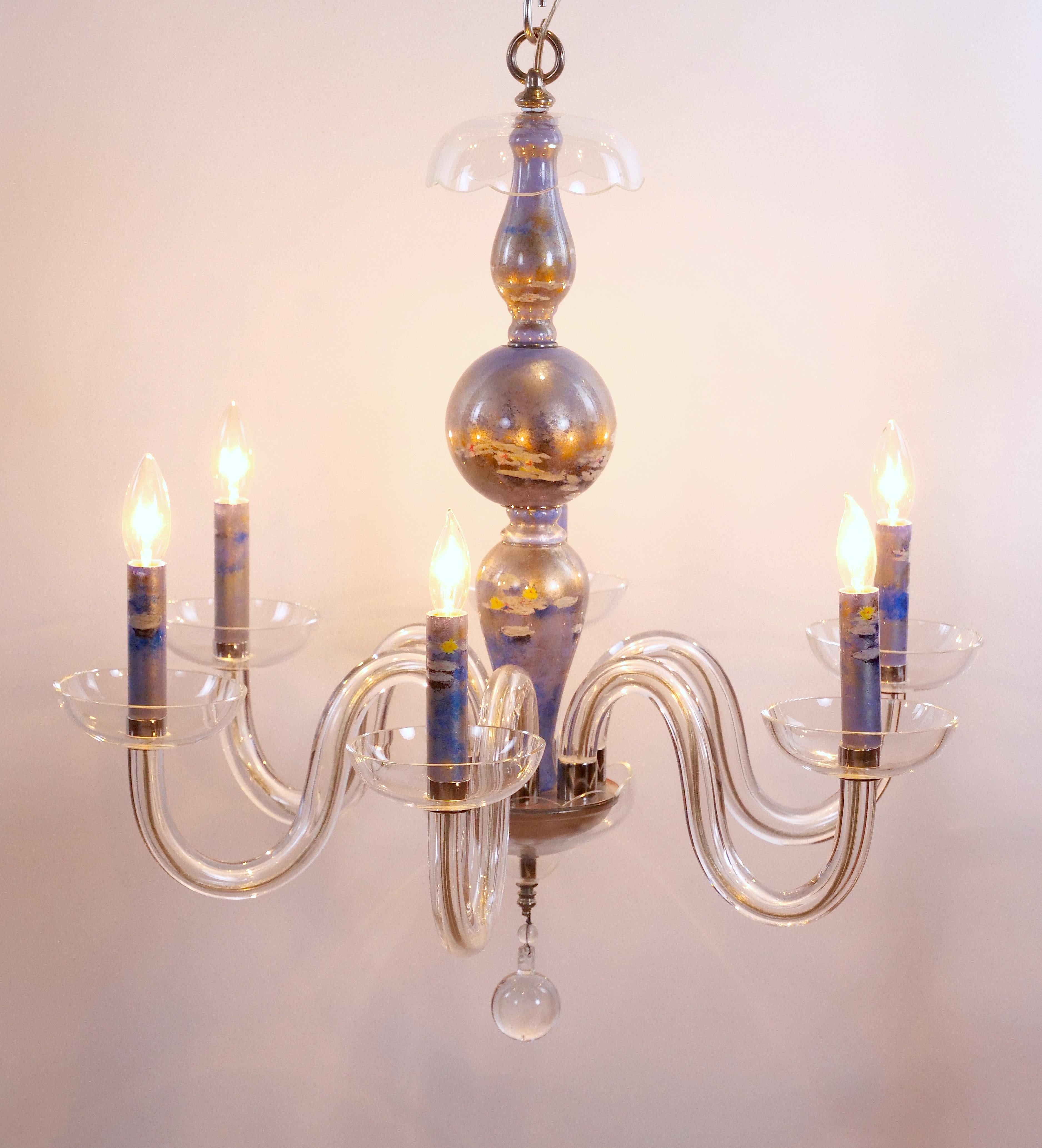 
Elevate your space with this exquisite Venetian Italian glass chandelier, handcrafted from clear blown glass and adorned with delicate silvered accents. The candle covers, tastefully designed, feature intricate hand painted water lilies set against