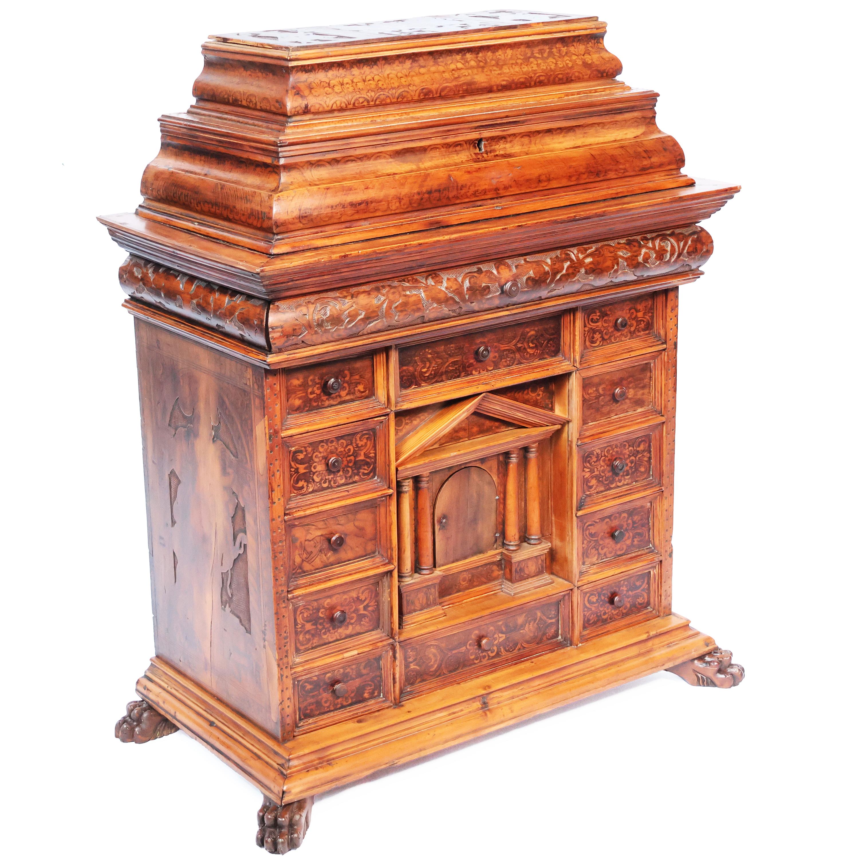 Descrizione
Monetiere in legno di noce e di cedro, intagliato e dipinto. Fronte lineare scandito da dodici cassetti che inquadrano un portale sormontato da un timpano, apribile e rimovibile, costituito da un cassetto alla base ed uno centrale. Il