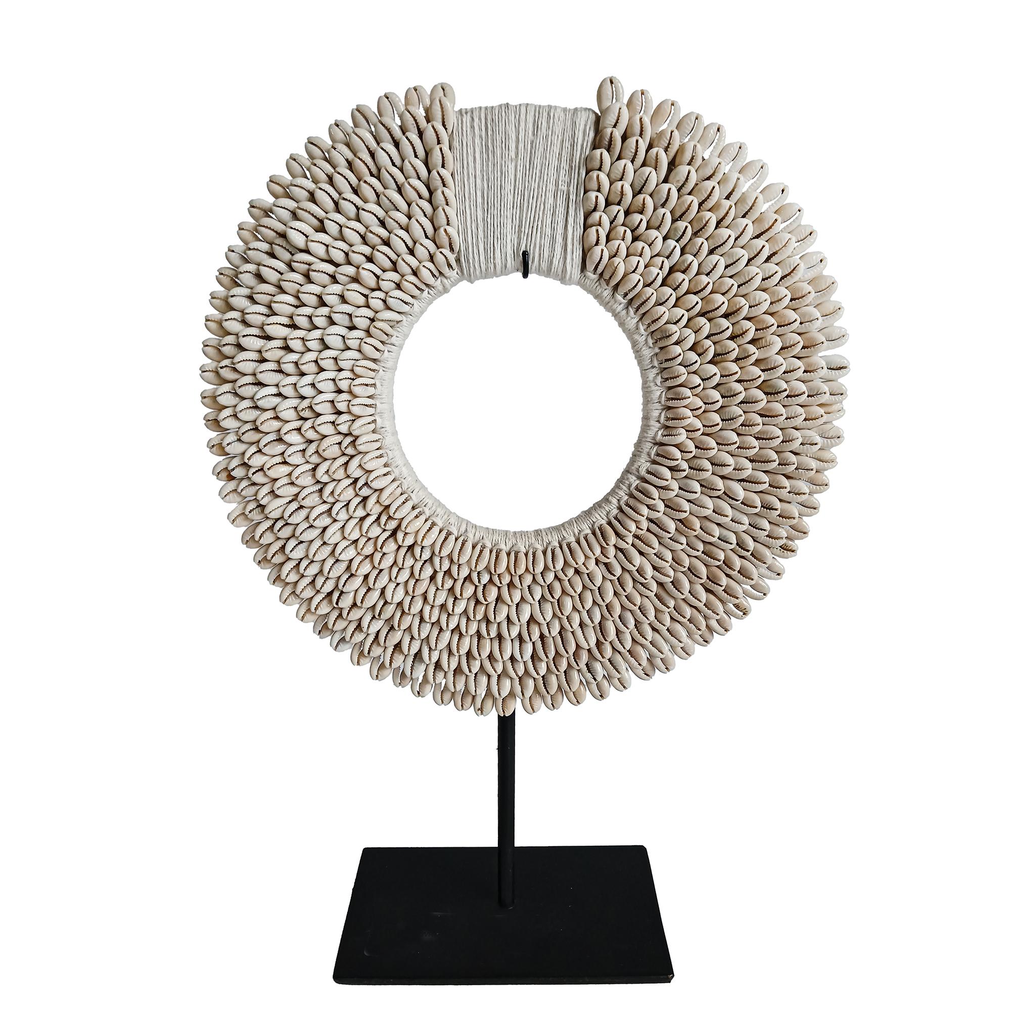 A male necklace from the Asmat Village, Papua New Guinea.

Tiny money cowrie shells seamlessly sewn in concentric rows around a hand-knotted macramé base, made out of white cotton wick. 

The necklace rests freely on a bespoke metal stand. This