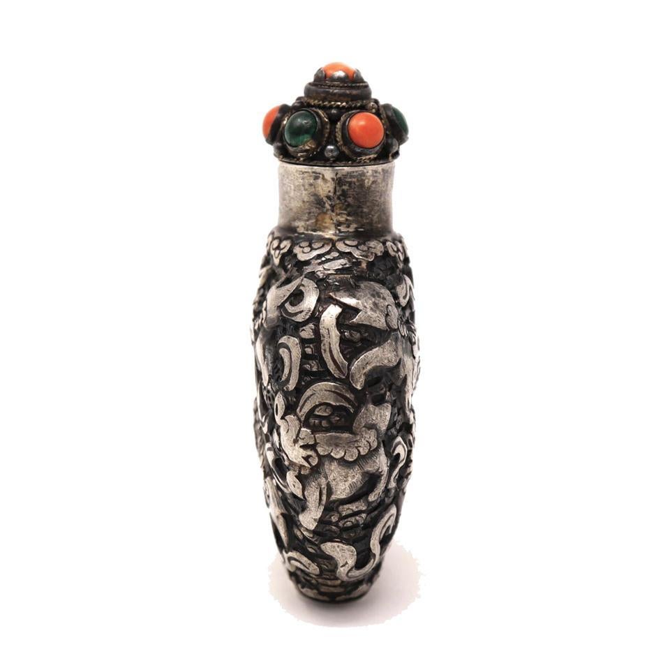 Mongolian style silver repoussé snuff bottle decorated with an overall design of nine lions playing with ribbon-tied balls, known as “Jiu Shih Toong Ju” (W-G), a wish for “May Nine Generations Live Together” a reference to achieving a harmonious