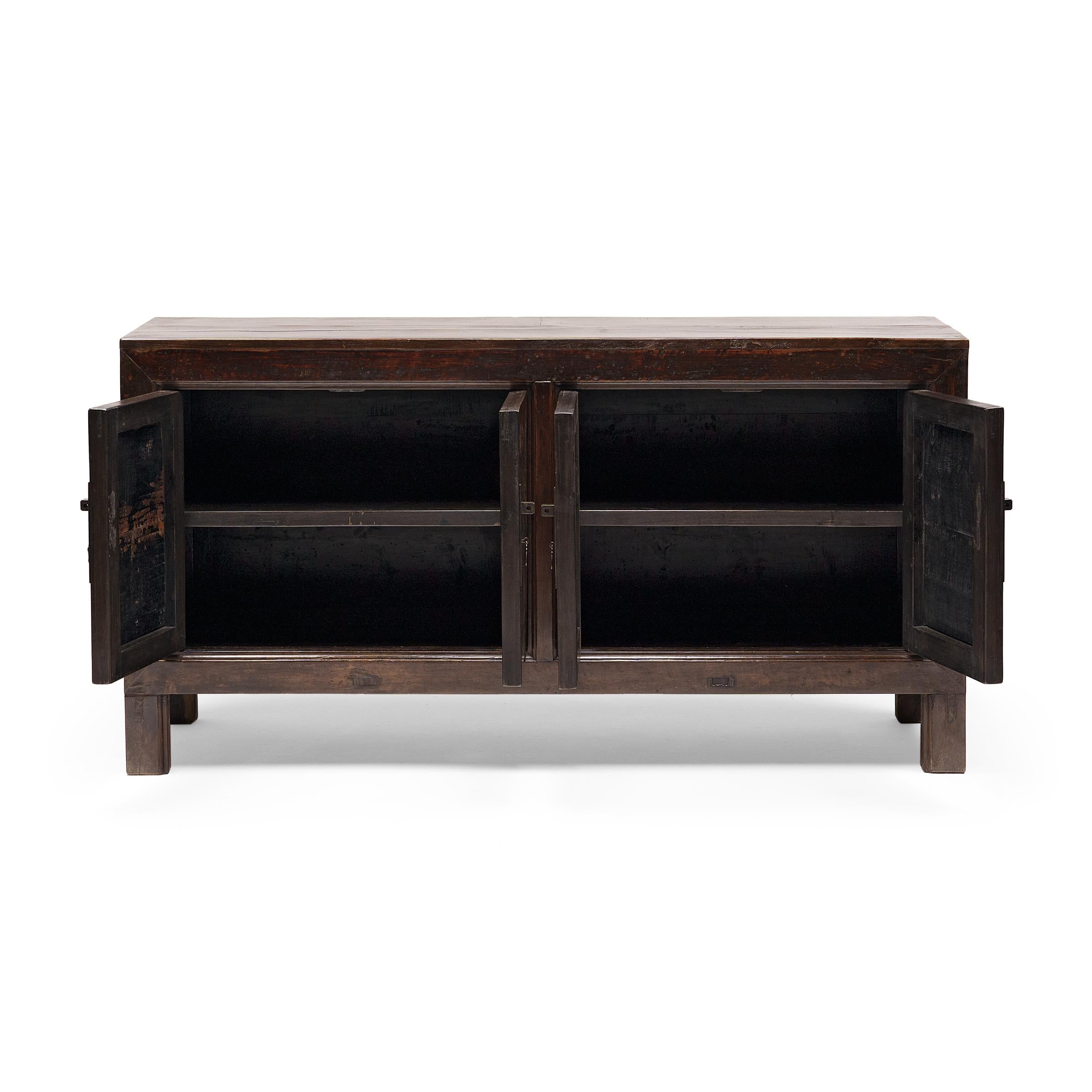 This 19th-century Mongolian storage coffer balances a streamlined silhouette with textured, wabi-sabi materials. Also referred to as a herdsman's chest, the four-door sideboard is expertly crafted of walnut using mortise-and-tenon joinery, without