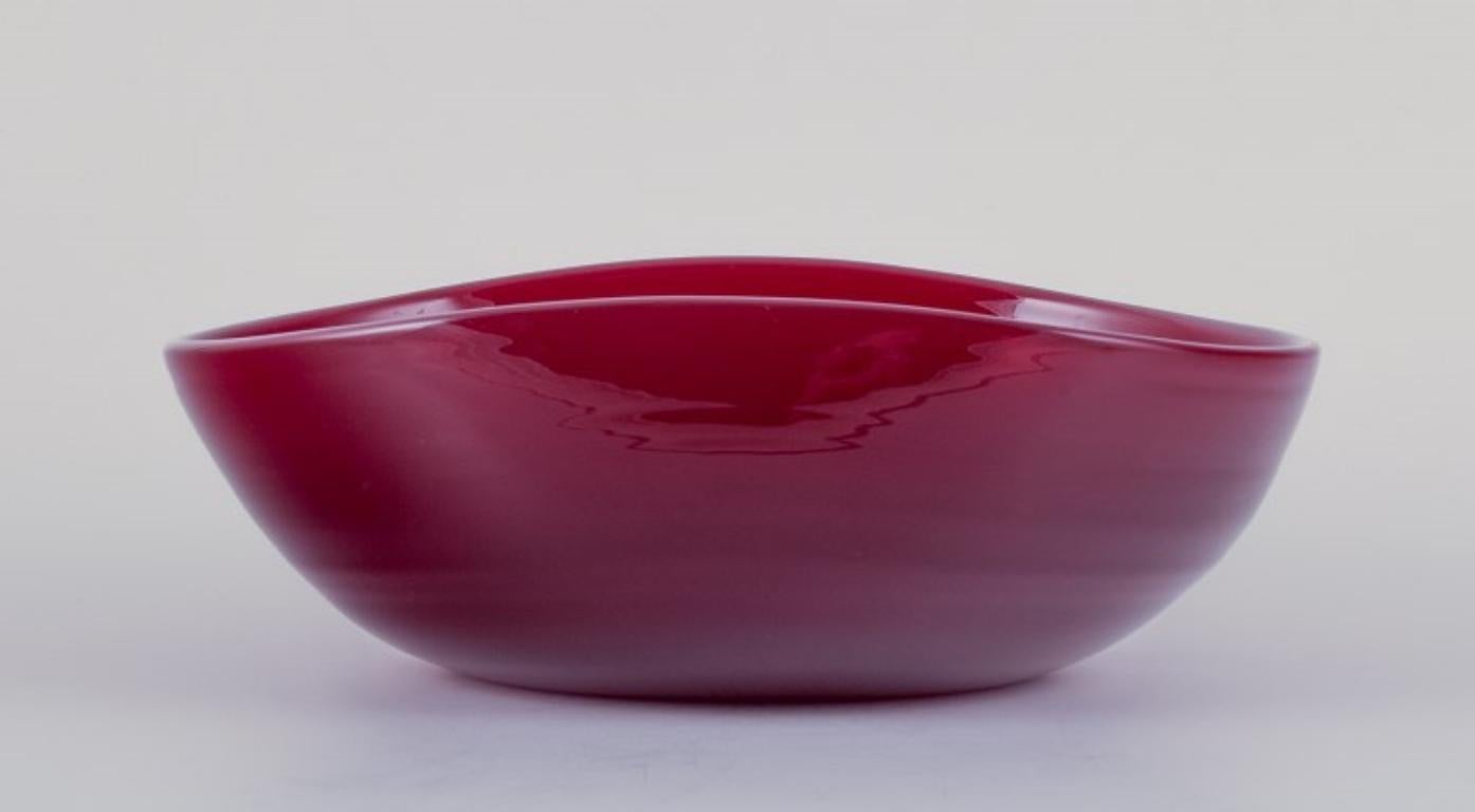 Monica Bratt for Reijmyre, Sweden. 
Large oval bowl in mouth-blown wine red art glass.
1960s/1970s.
Perfect condition.
Dimensions: L 24.7 cm x W 19.8 cm x H 7.0 cm.

Founded in 1810 in the southern region of Sweden, Reijmyre Glassworks gained